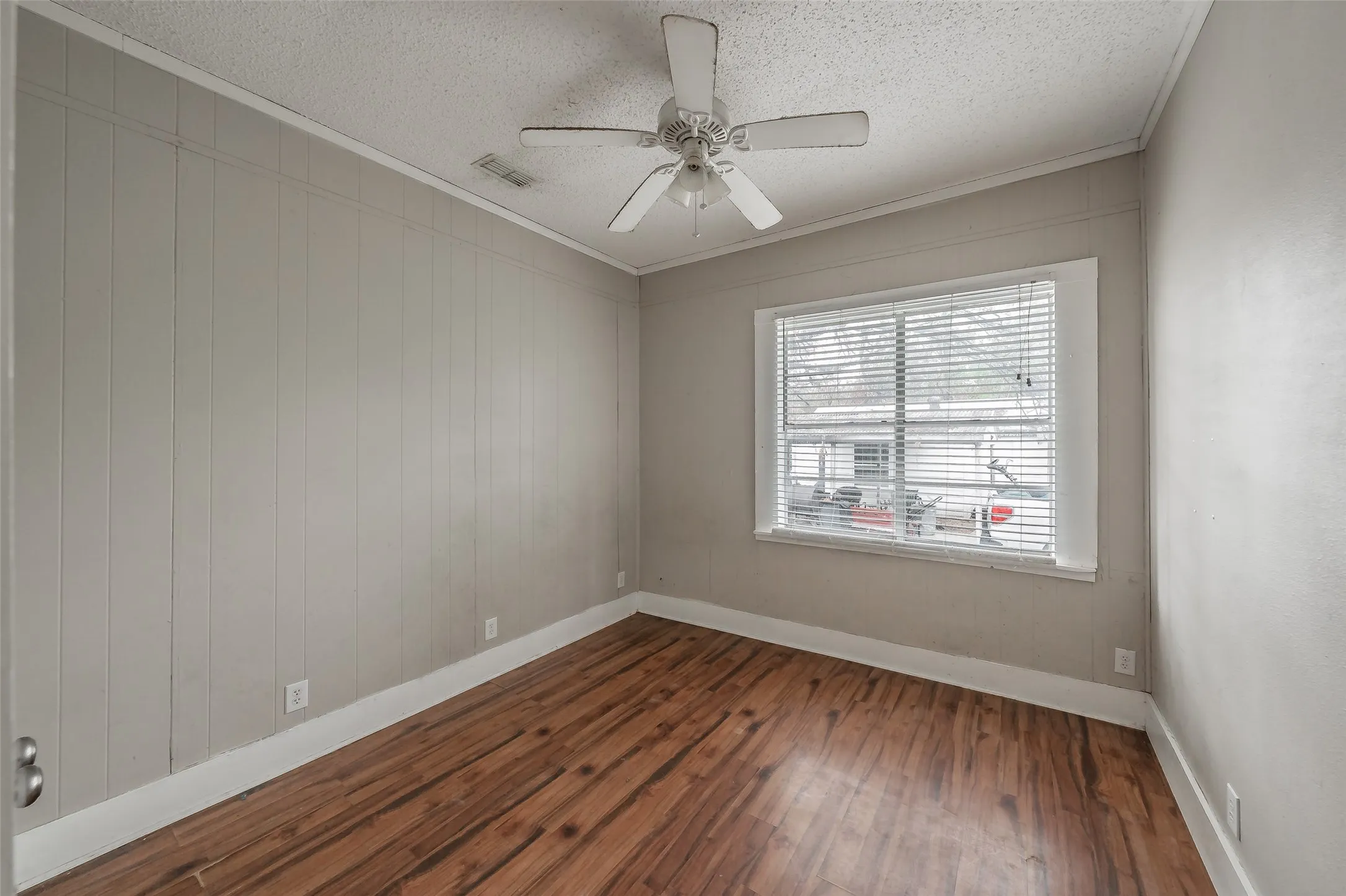 Wood-finish flooring, ceiling fan, and window with blinds