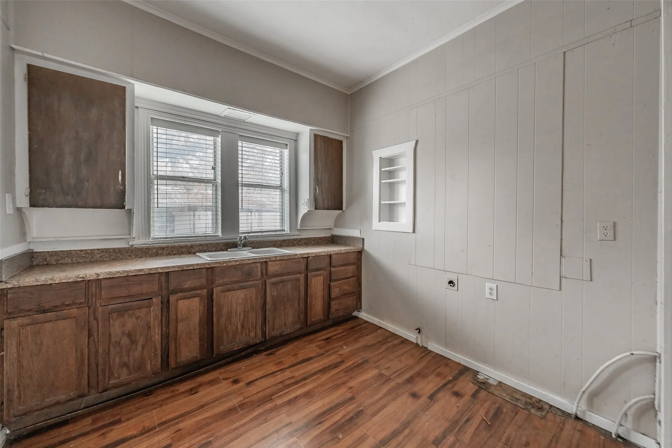 Wood-finish flooring, extensive lower cabinetry, built-in dual sink, and a built-in wall shelf