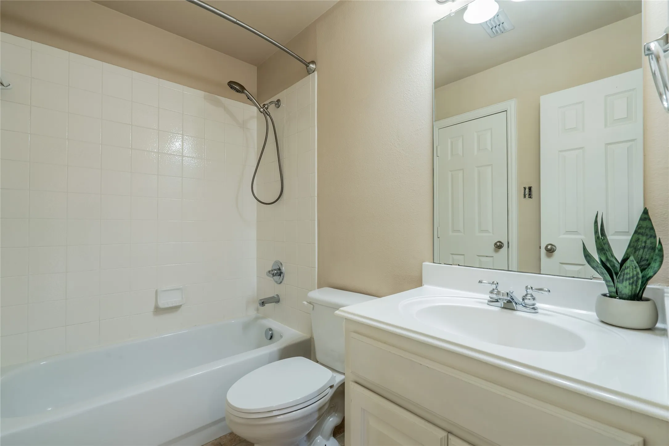 Second upstairs bathroom with white tile shower surround, chrome shower fixtures, white bathtub, white vanity with integrated sink, chrome vanity faucet