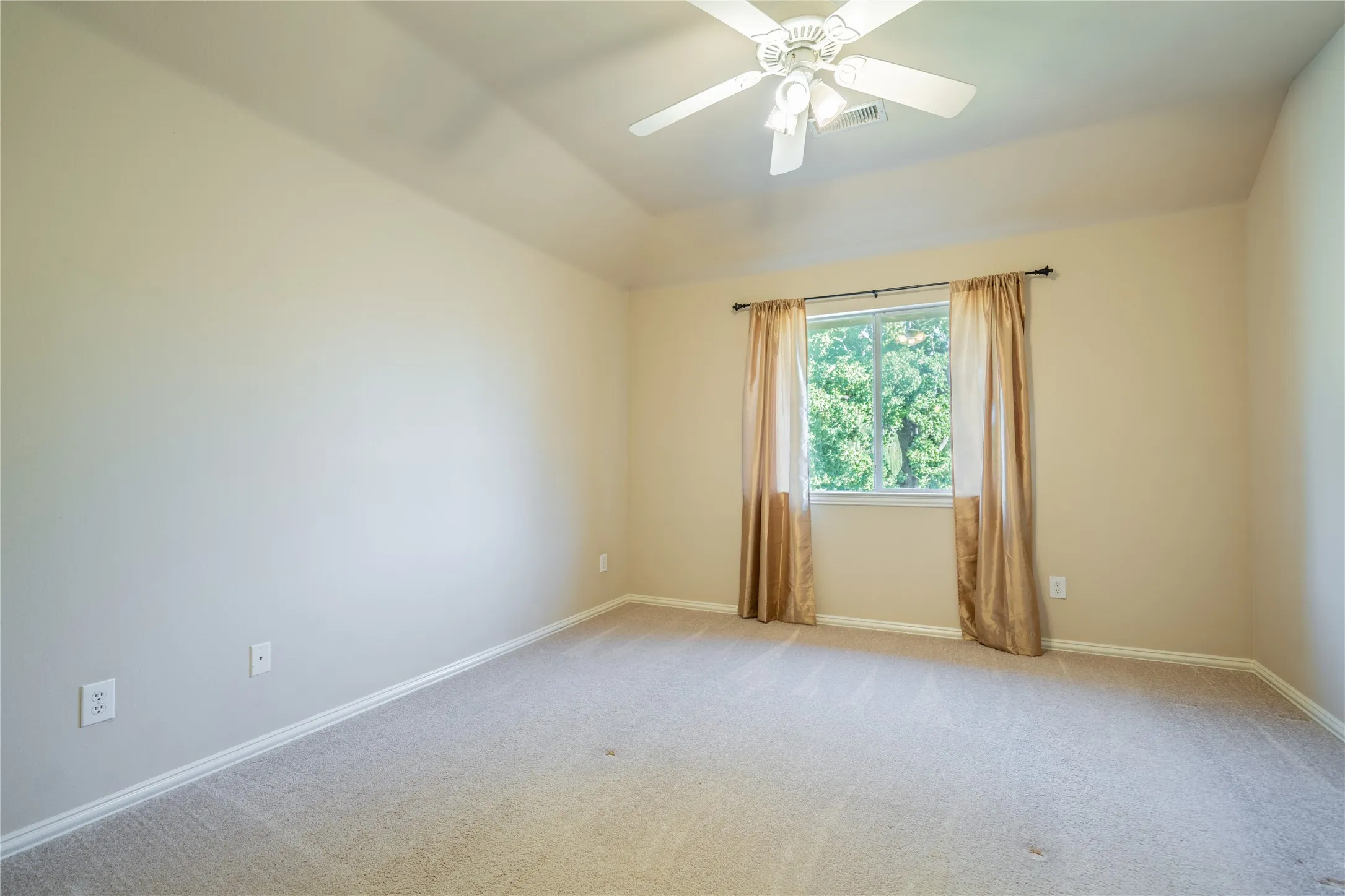 Bedroom with recessed ceiling with an overhead fan, neutral wall tones, and carpet flooring