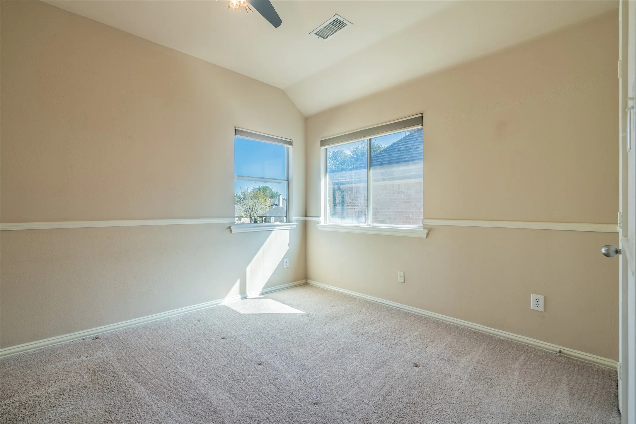Bedroom with vaulted ceiling with a ceiling fan, carpeted flooring, and multiple windows