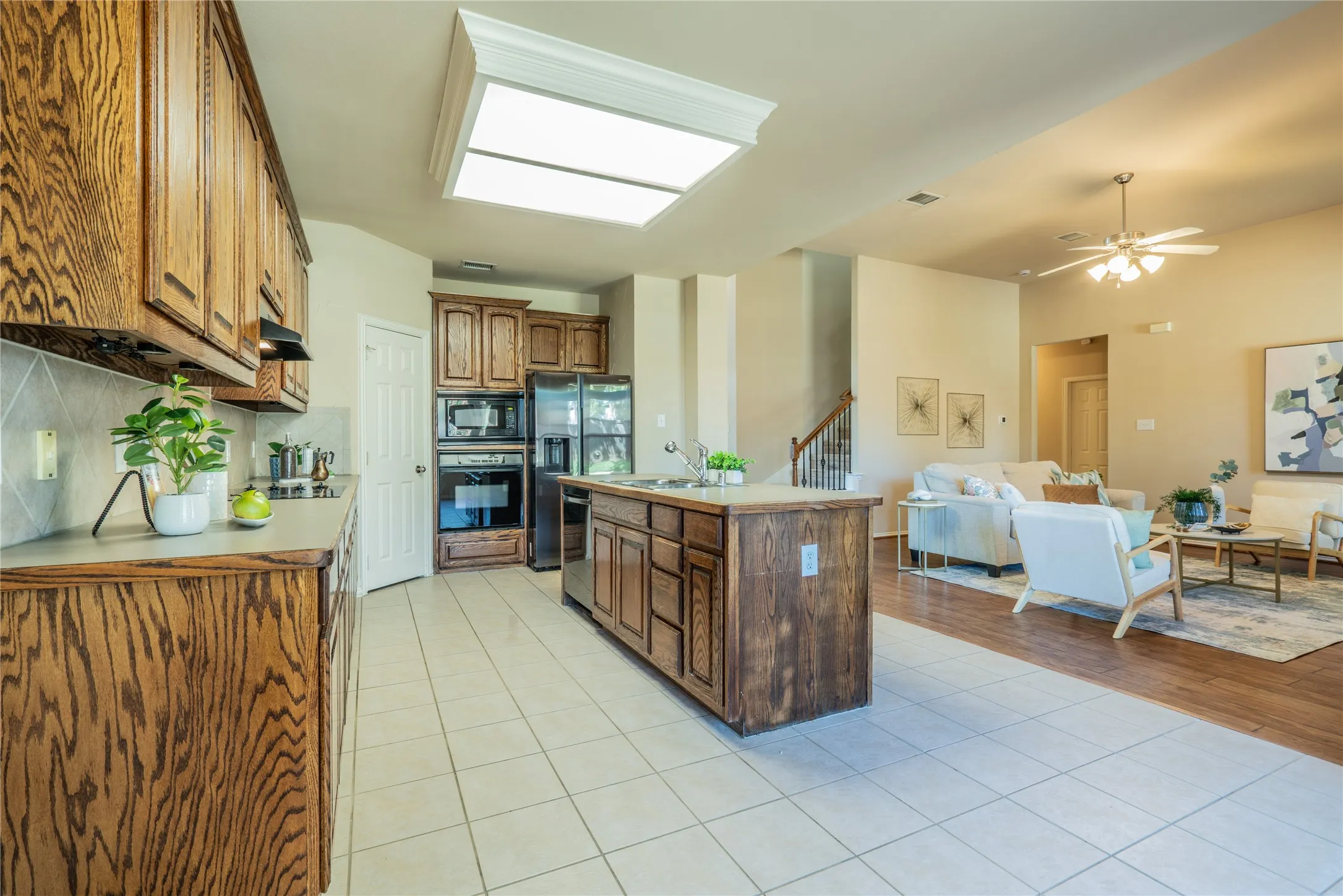 Kitchen with wood-finish cabinetry, tile flooring, and a central island