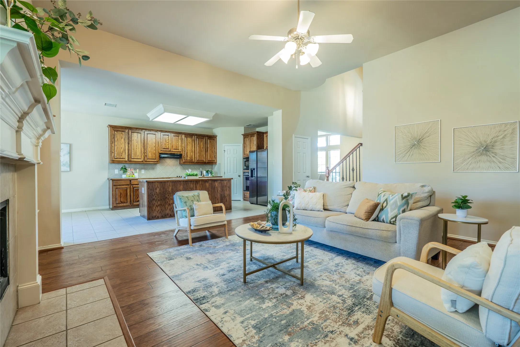 Living area with vaulted ceiling, wood-finish flooring, fireplace, and ceiling fan