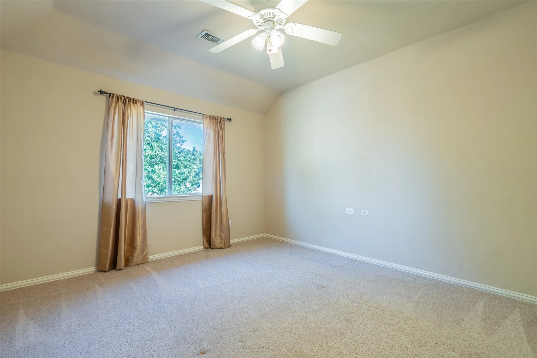 Another view of the bedroom with a recessed window with white trim, beige wall finishes, and a ceiling fan with integrated lighting