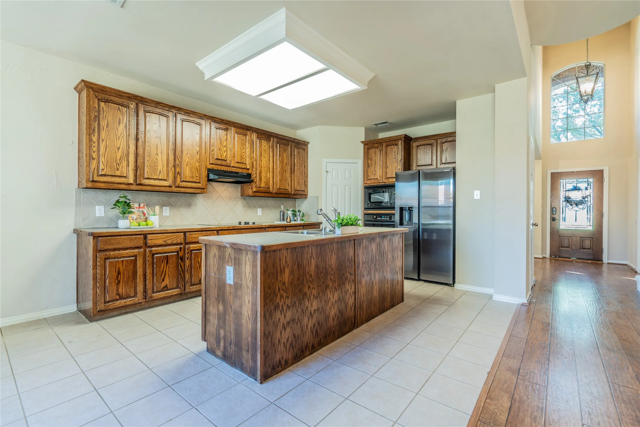 Kitchen featuring wood cabinetry, a central island, stainless steel appliances, and tile flooring