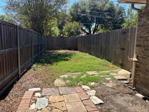 Fenced backyard featuring a wooden privacy fence, and a stone and brick paver pathway