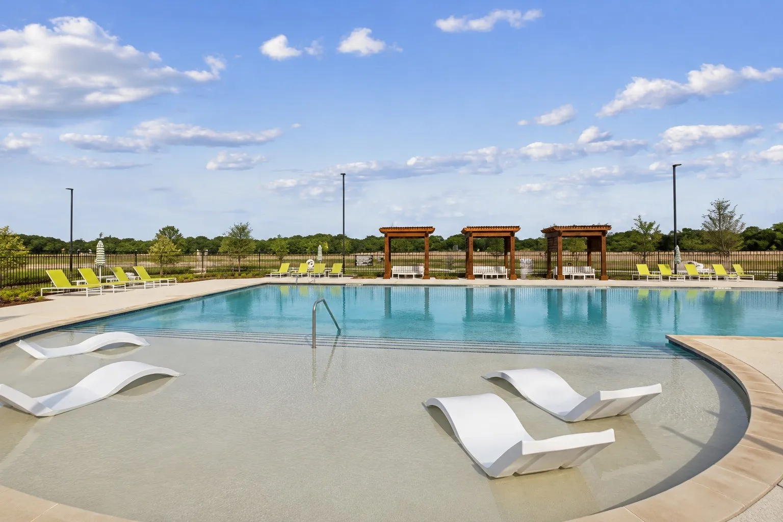 Expansive swimming pool with integrated sun shelf, multiple in-pool lounge chairs, and surrounding pergolas