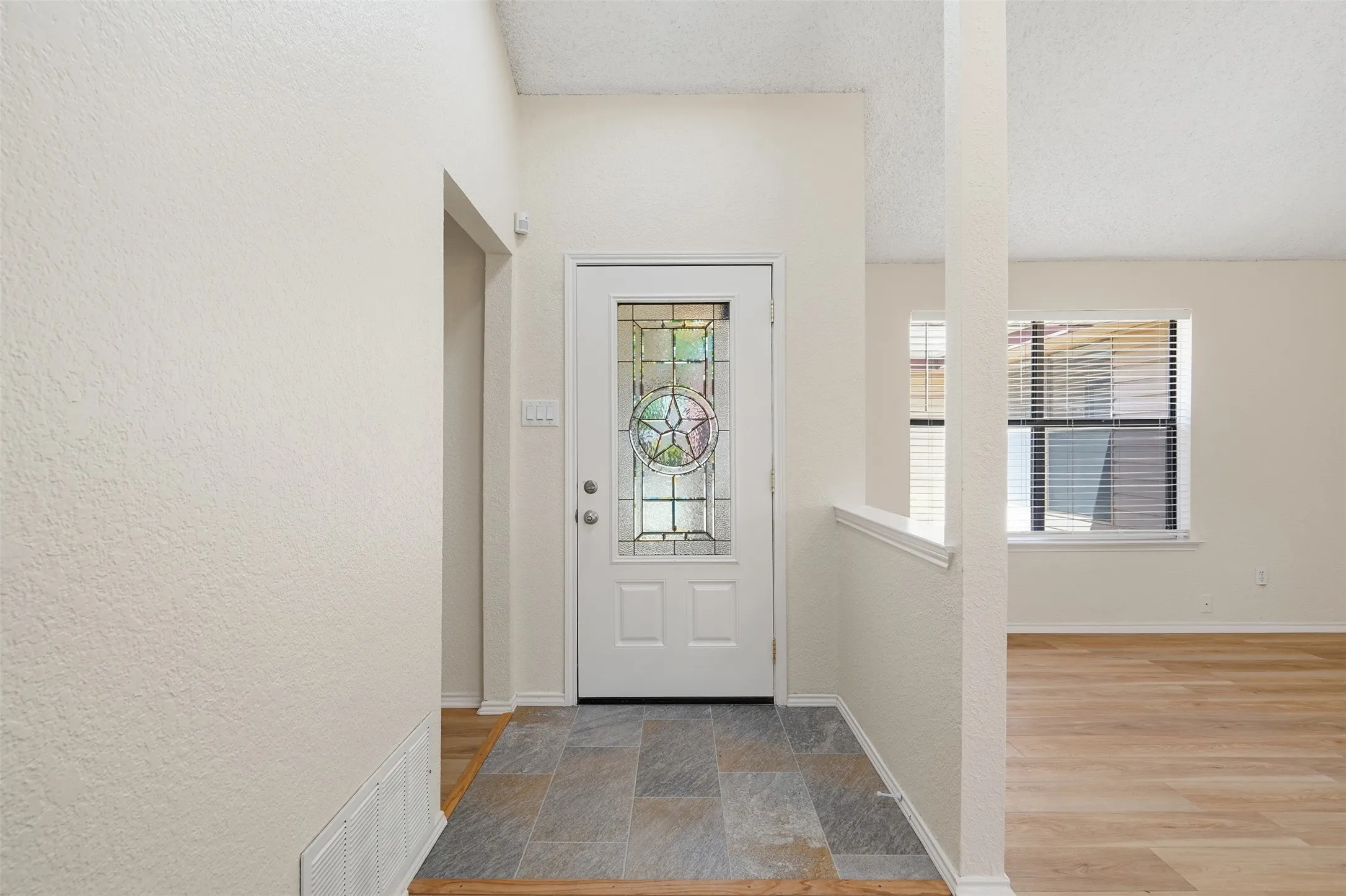 Entryway featuring a decorative glass paneled door, slate-look tile flooring, and wood-finish flooring