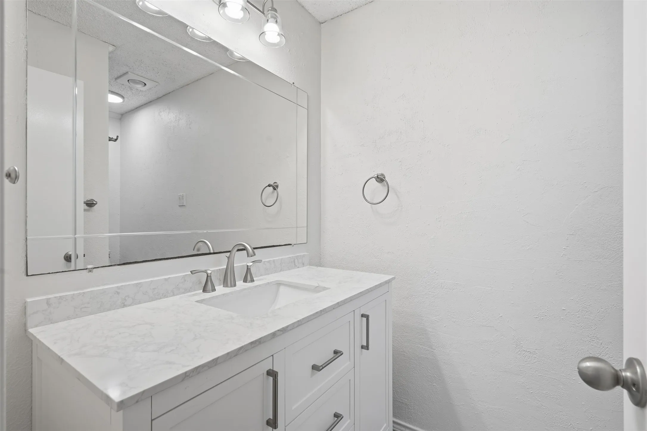 White vanity with brushed nickel hardware, integrated rectangular sink, and a light-toned countertop