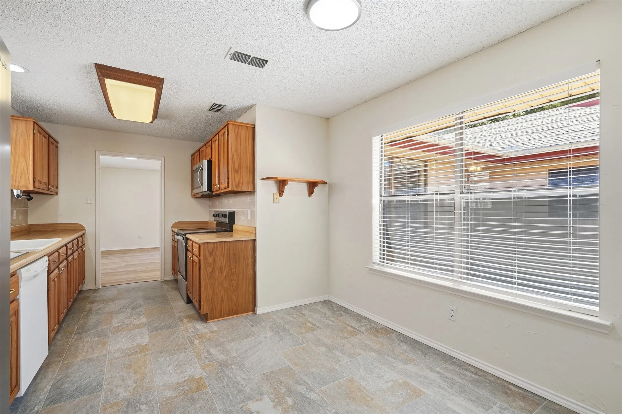 Kitchen featuring wood-finish cabinetry, built-in microwave, and tile flooring