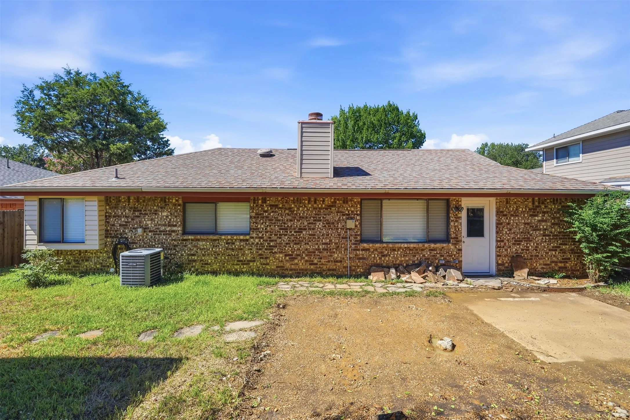 Brick exterior with a shingle roof and a white rear entry door