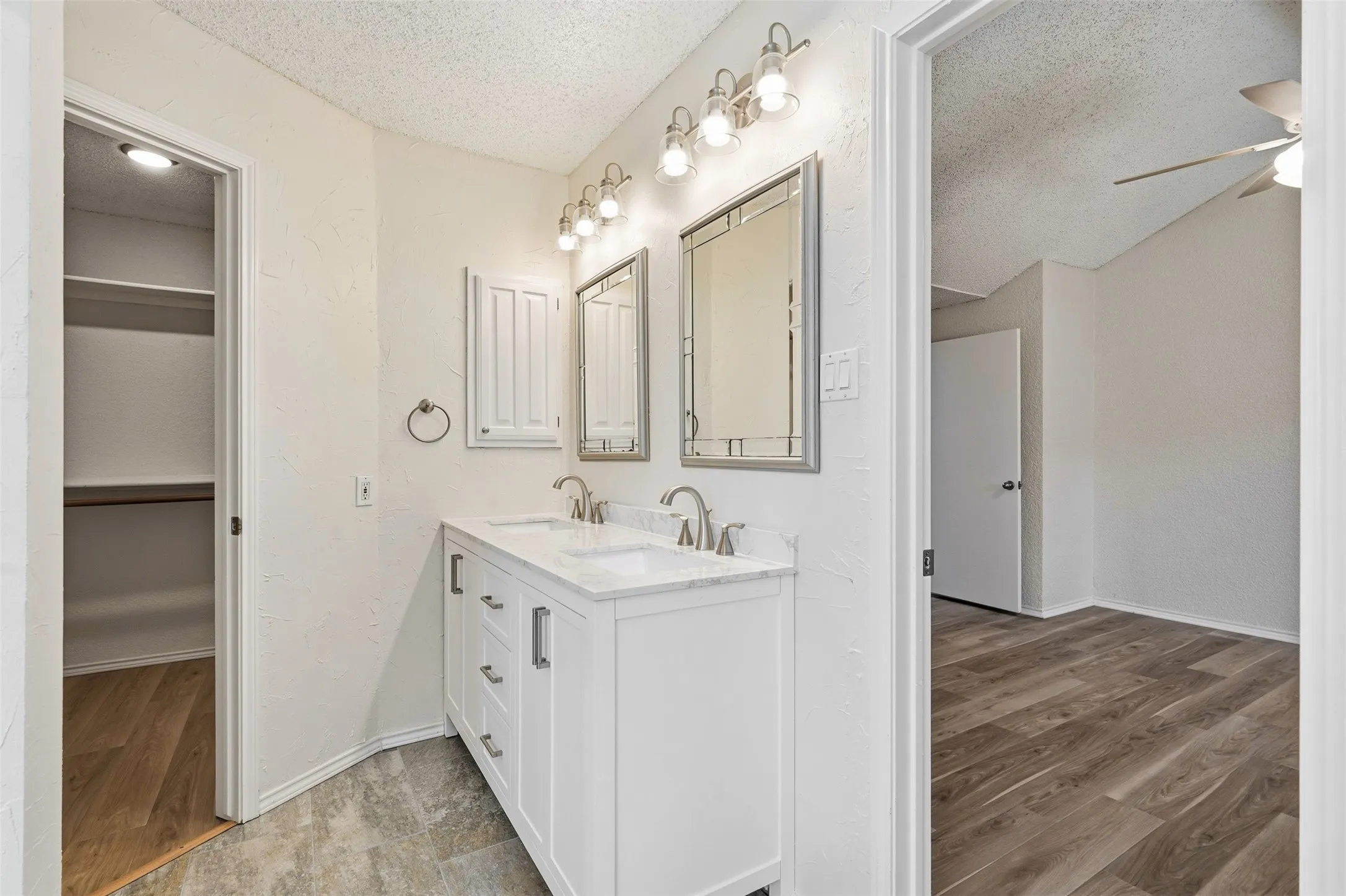 Dual vanity with white cabinetry, integrated sinks, and polished chrome fixtures