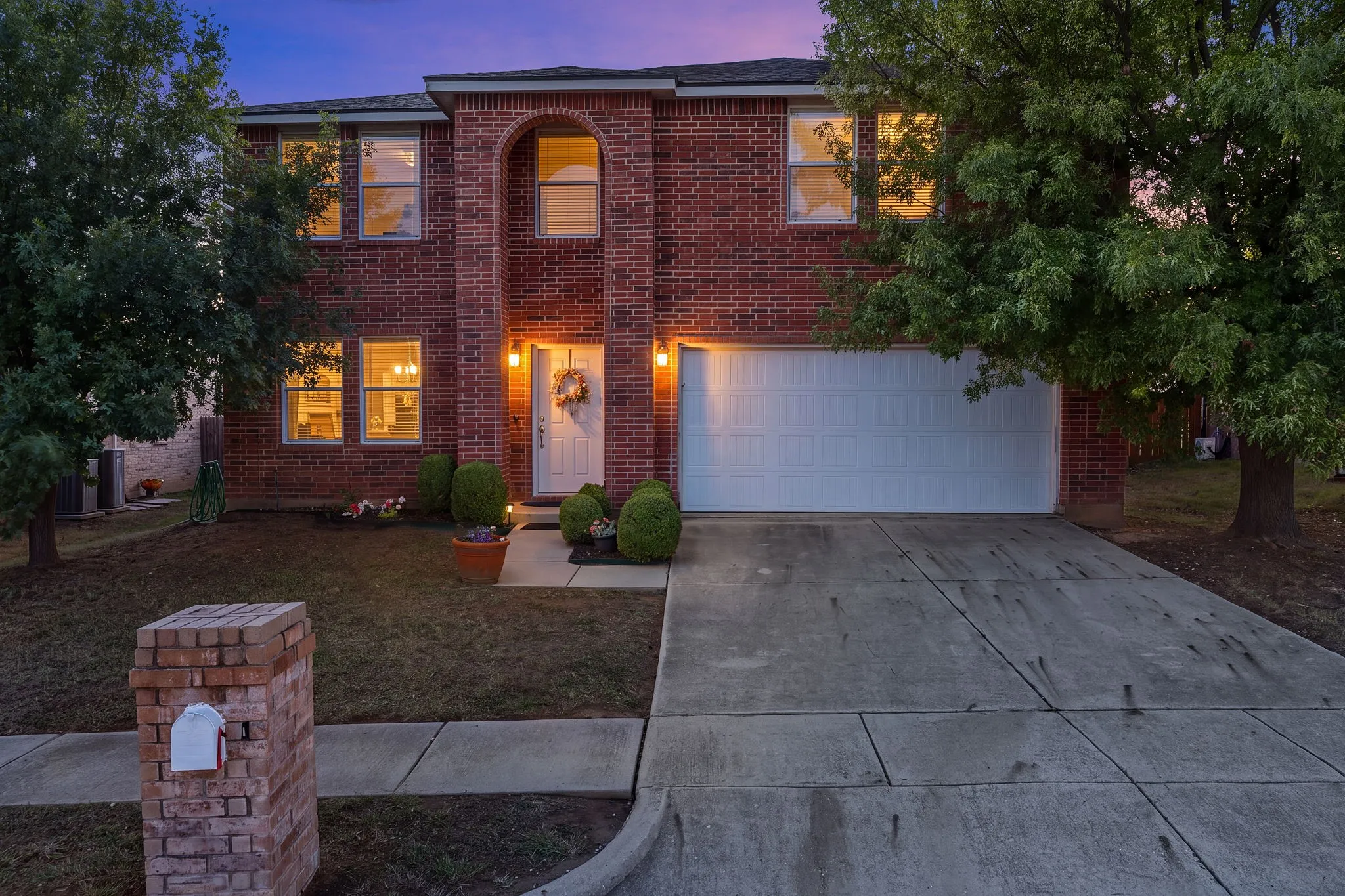 Brick exterior with an arched window accent, white front door, and an attached two-car garage