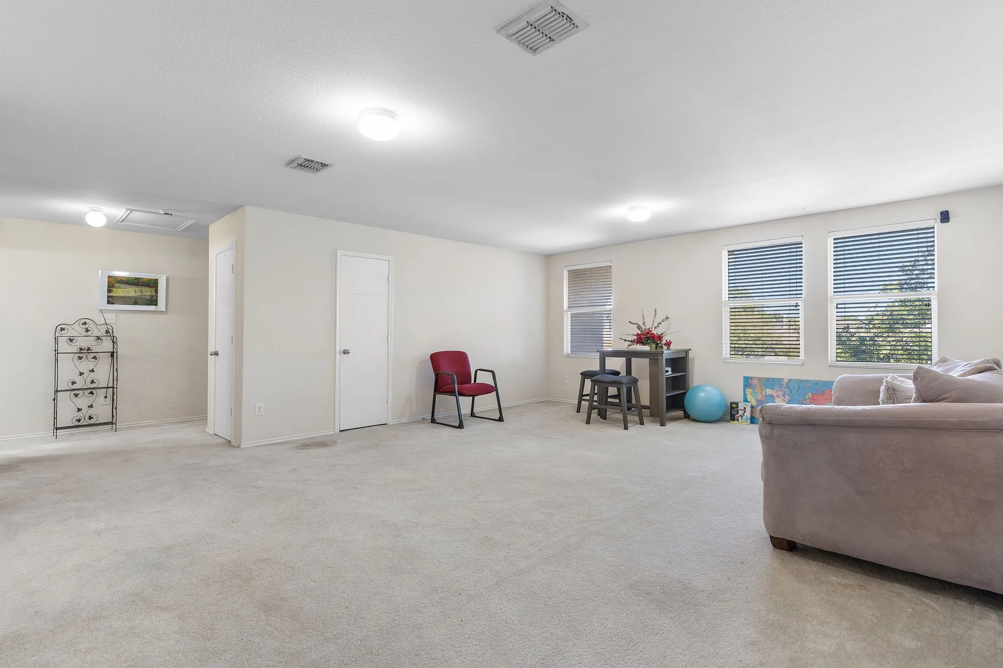 Carpeted living area featuring multiple windows, white walls, and flush-mount ceiling lights