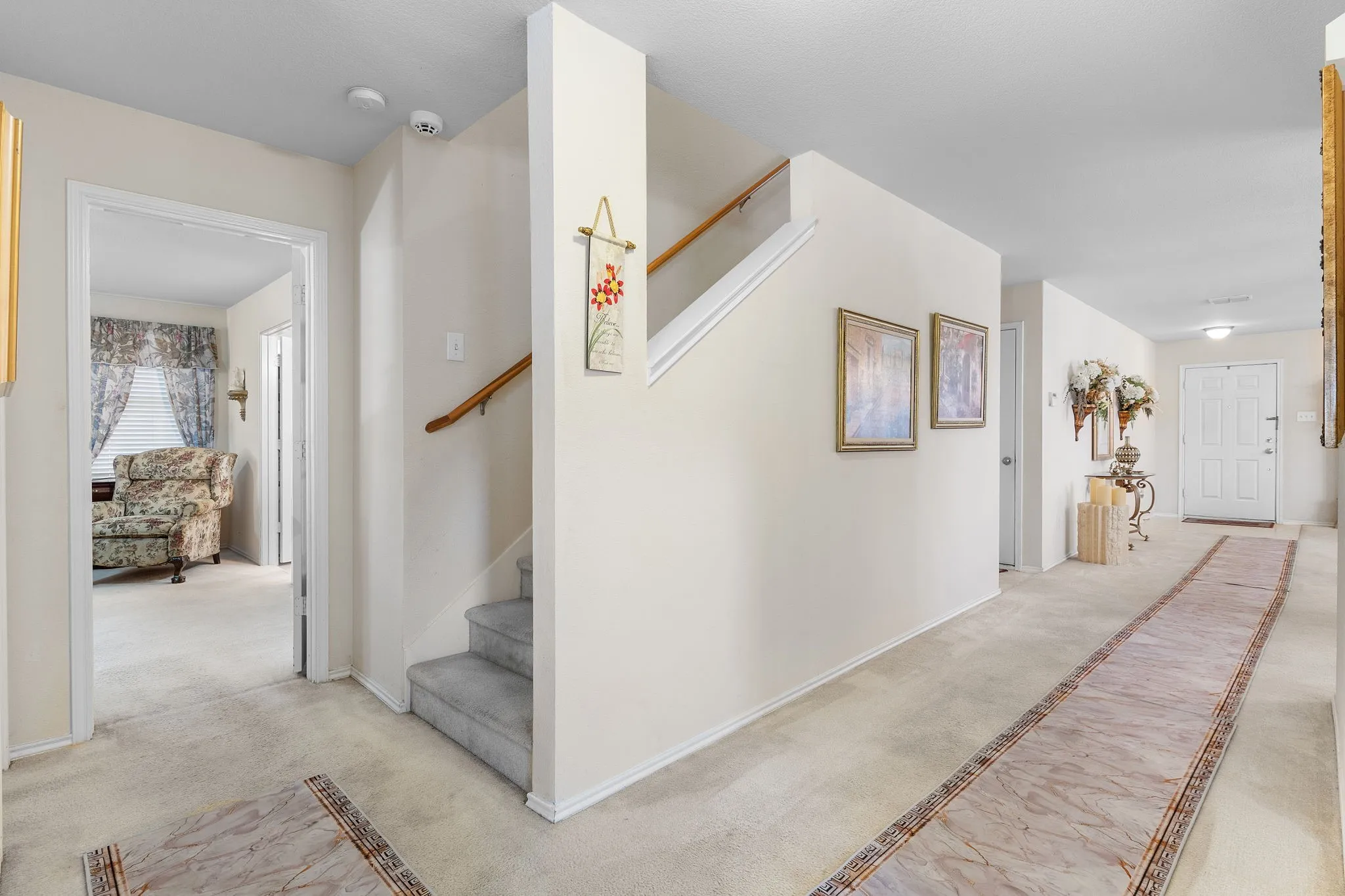 Entry foyer with carpet flooring, staircase with wood handrail, and paneled entry door
