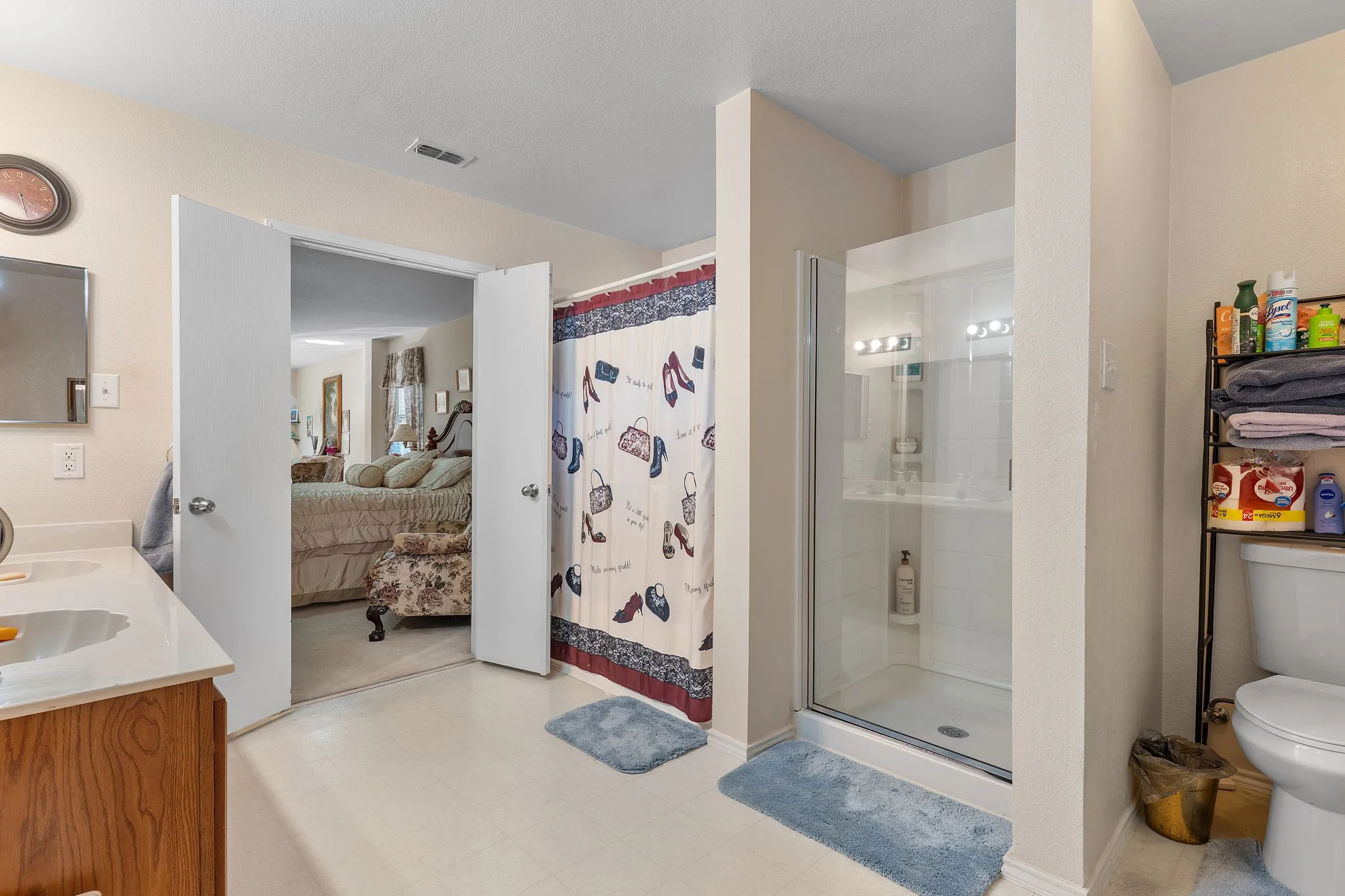 Dual vanity with a laminate countertop, a glass-enclosed shower, and a white toilet