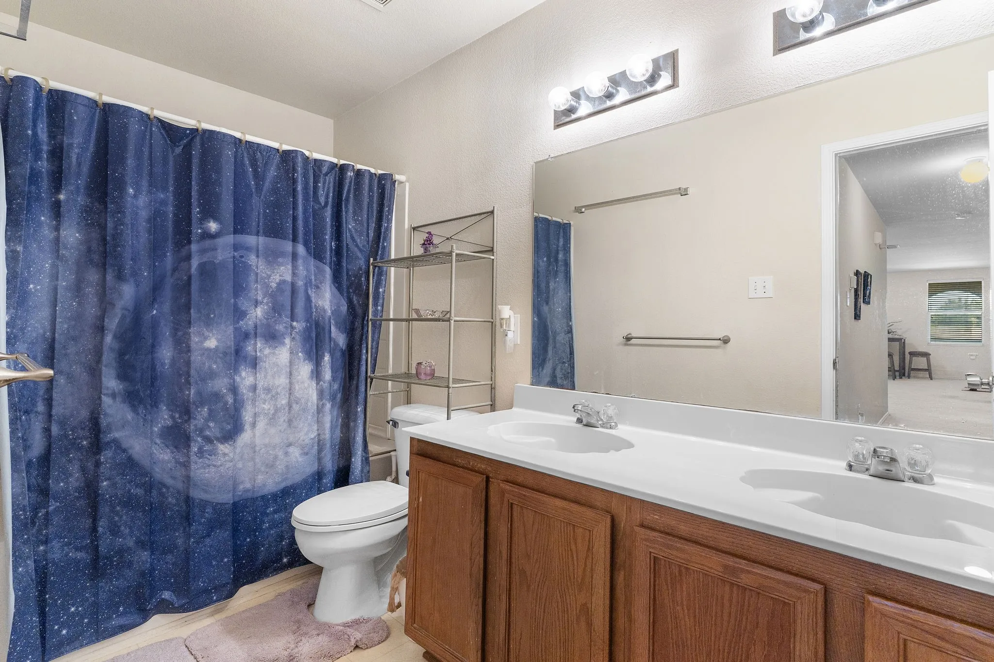 Double vanity with integrated sinks, wood-finish cabinetry, and an expansive wall mirror