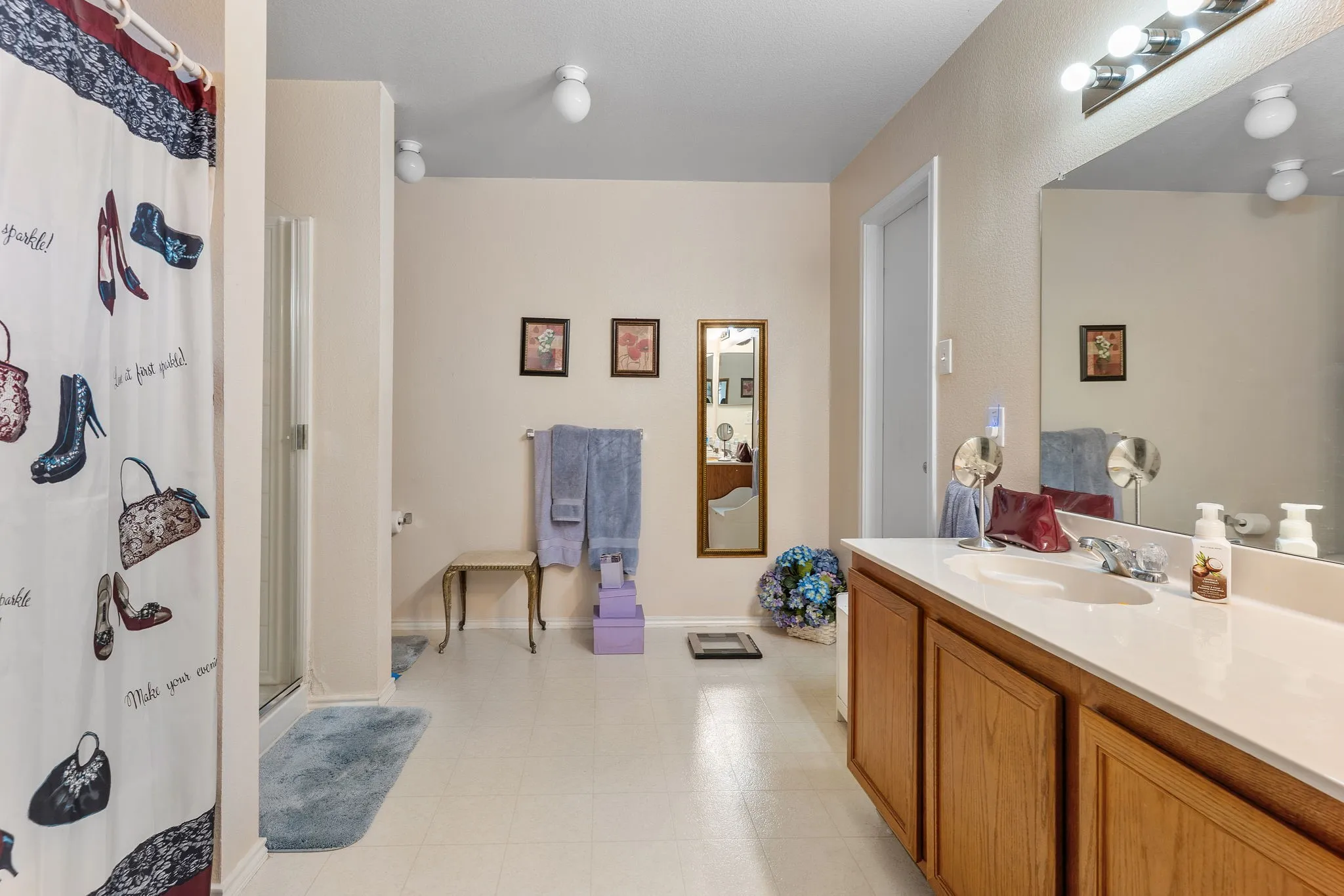 Double vanity with integrated sink, wood-finish cabinetry, and overhead lighting