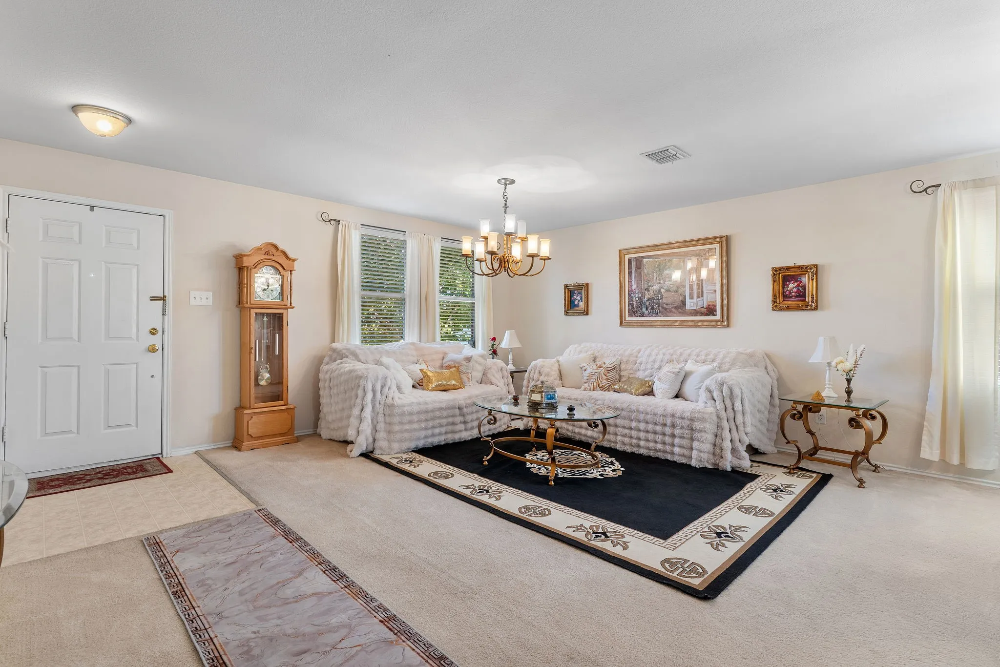 Neutral wall colors, chandelier lighting, multiple windows, front door with paneling, and wall-to-wall carpeting