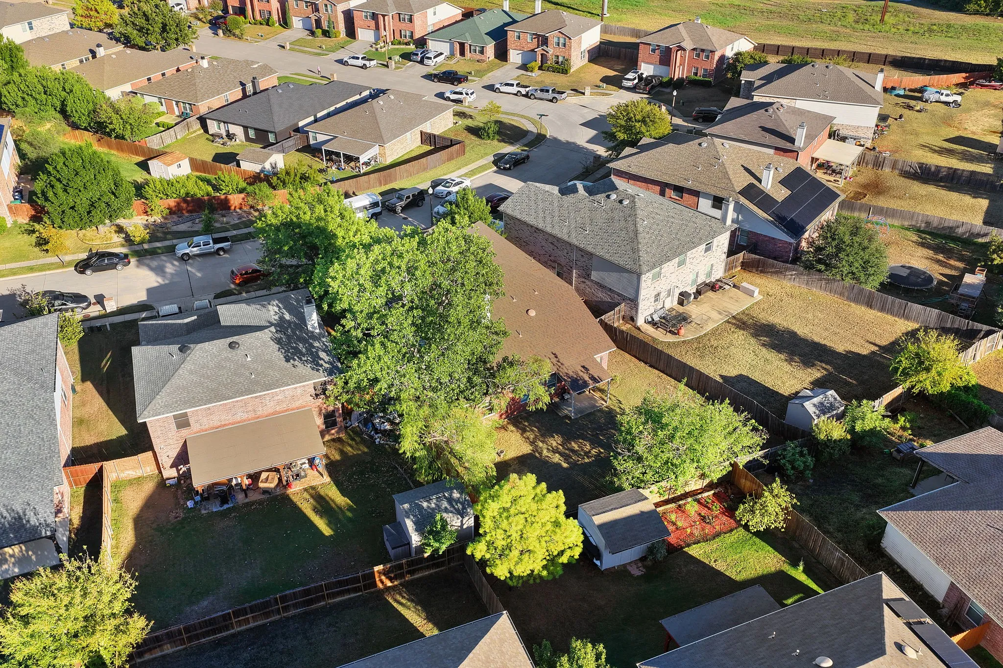 Brick exterior, solar panels, fenced yard, paved patio, and mature trees