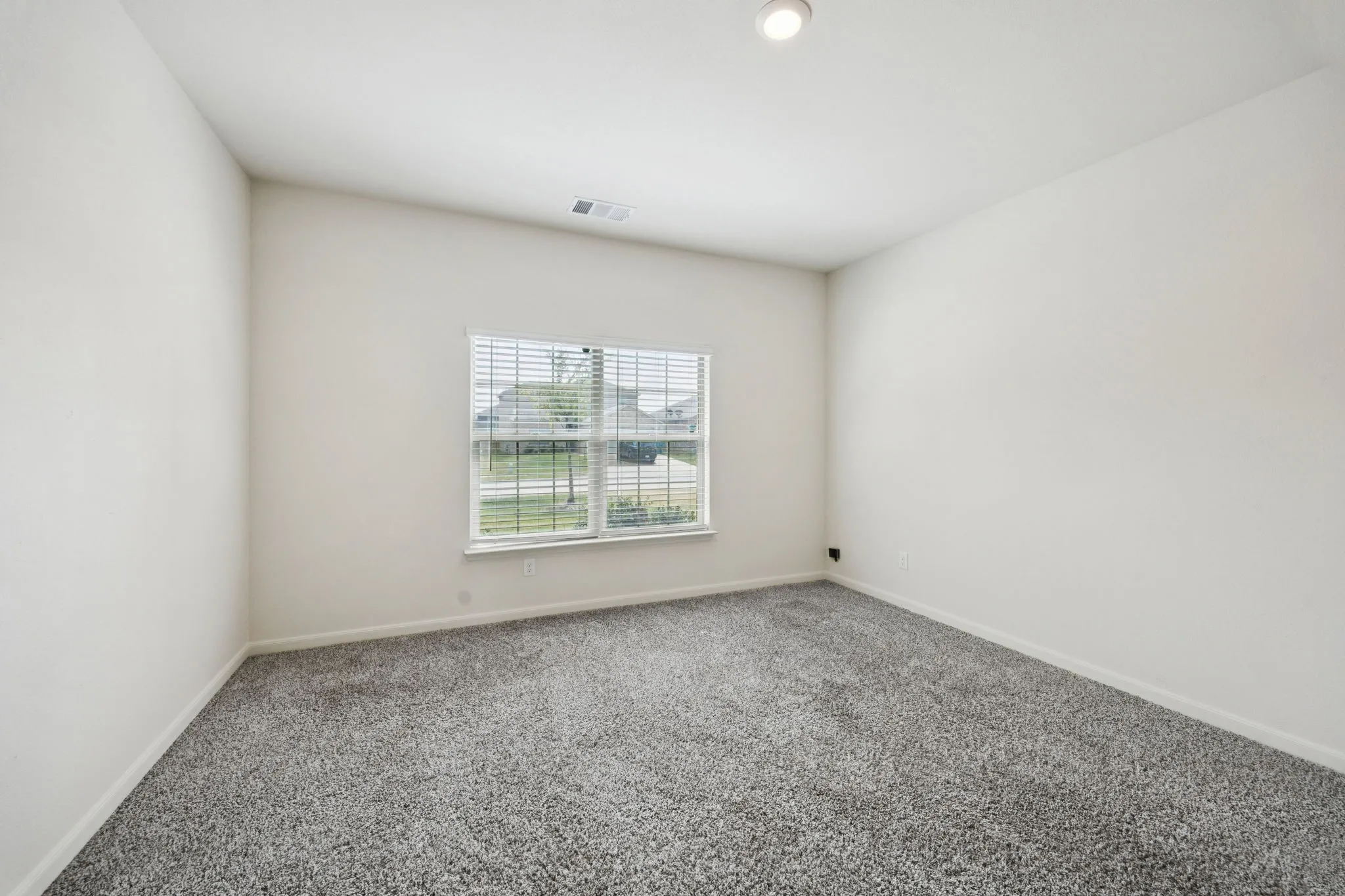 Neutral wall paint, gray carpeting, window with horizontal blinds, recessed ceiling light, and ceiling air vent