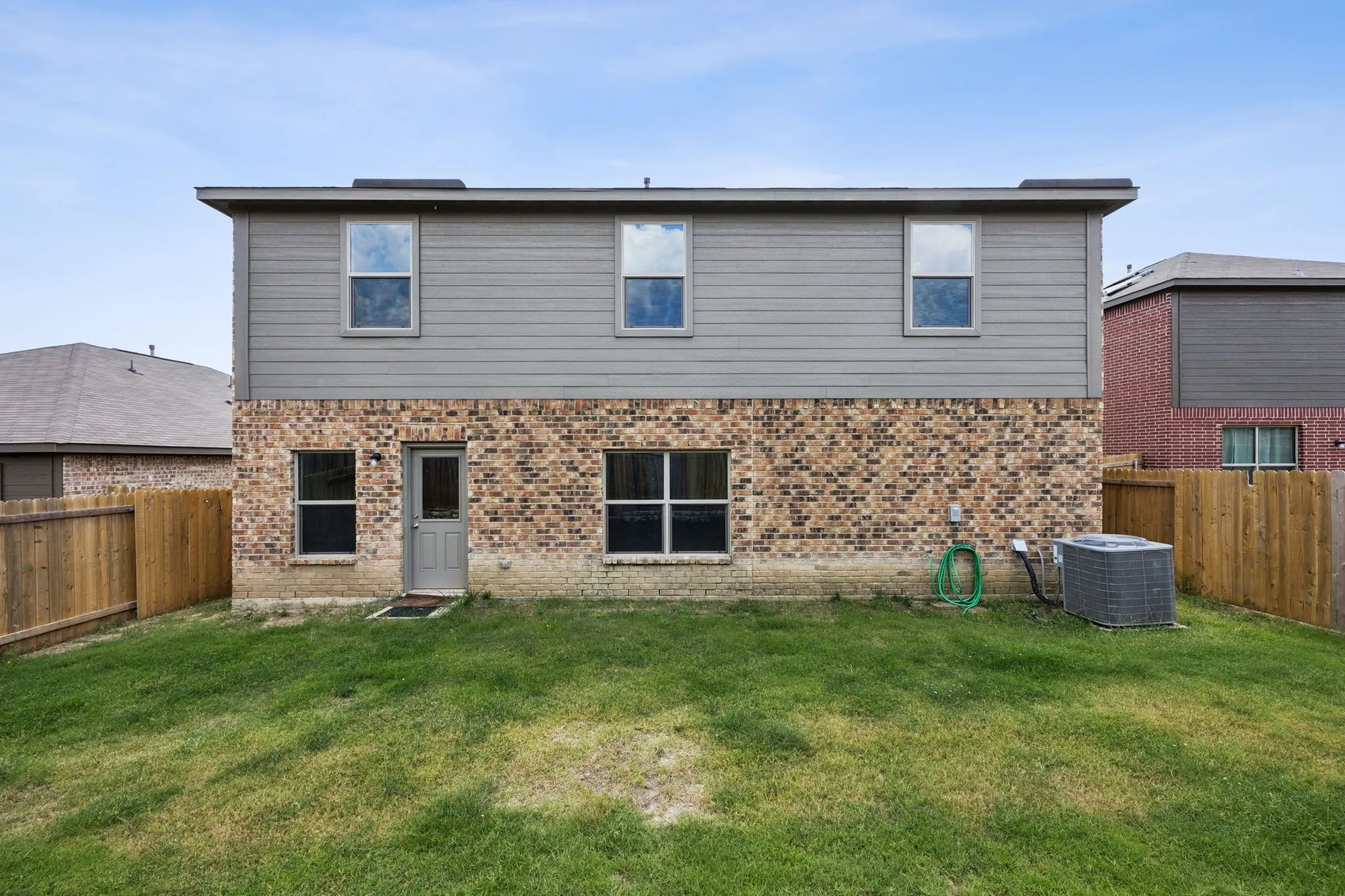 Exterior featuring brick and siding finishes, multiple windows, and a private fenced yard
