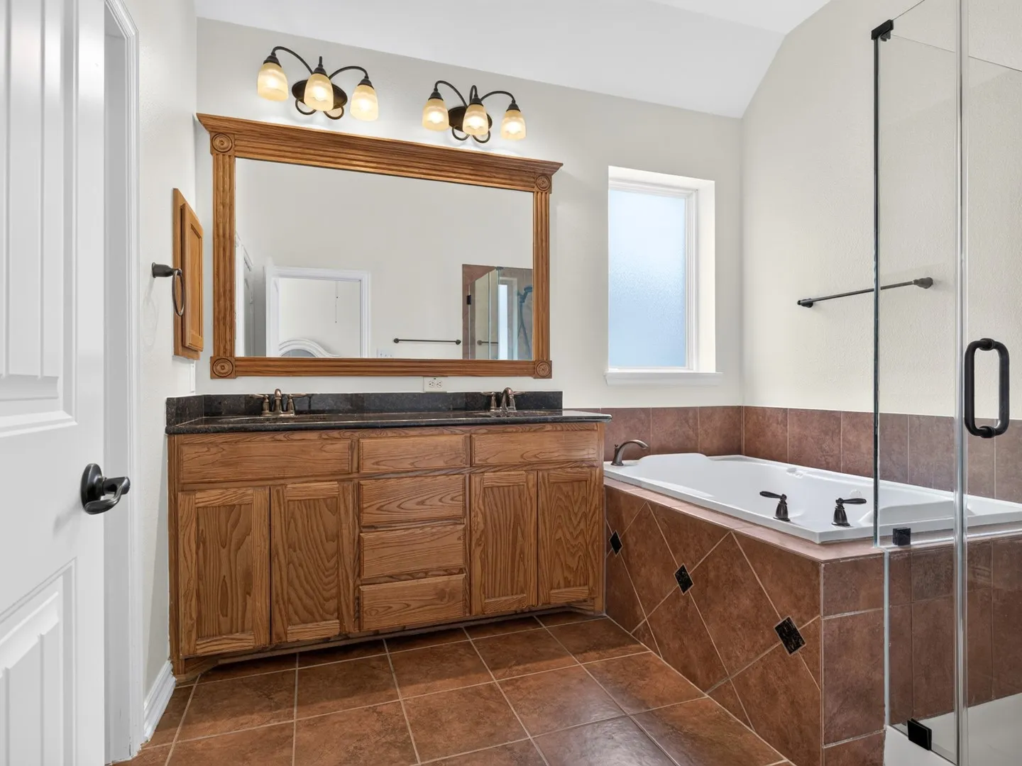 Double vanity with wood-finish cabinetry and dark countertop