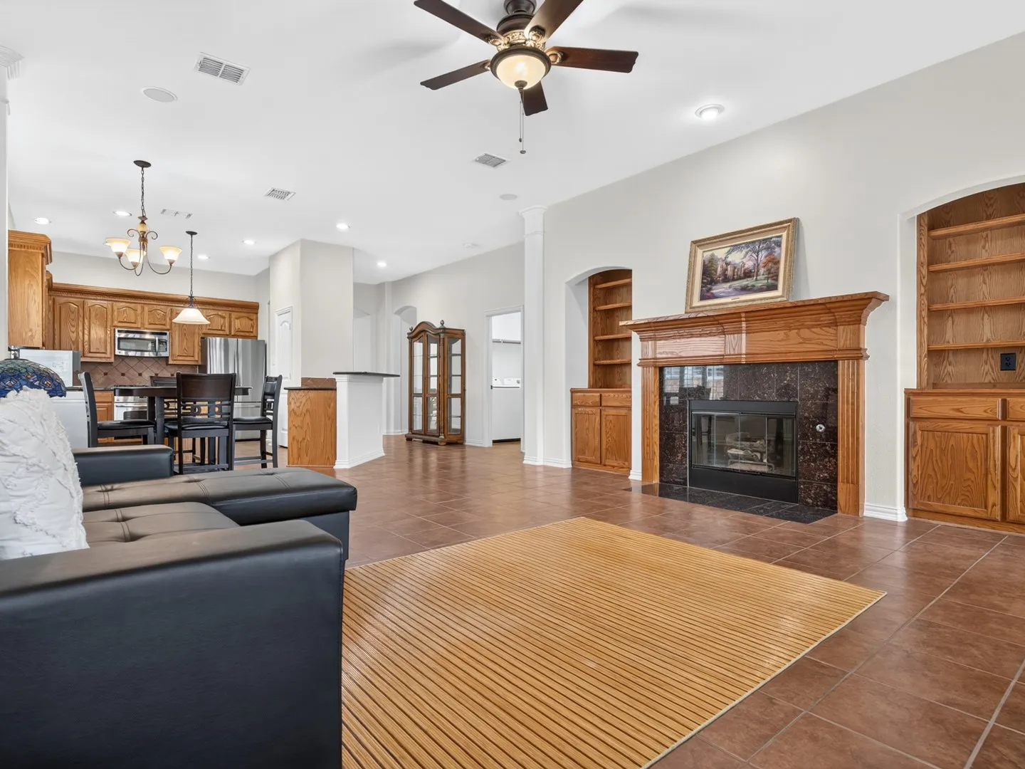 Tile flooring, fireplace with wood mantel and dark stone surround, built-in shelving, wood cabinetry, and recessed lighting