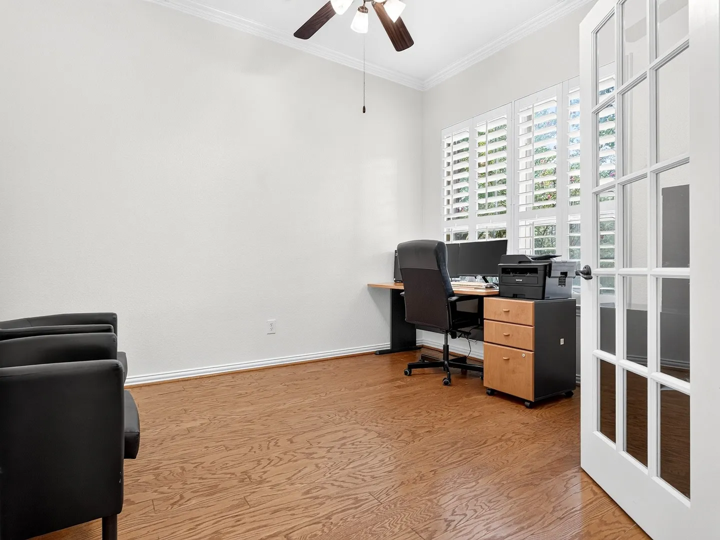 French doors with divided lites, wood-finish flooring, plantation shutters, and a ceiling fan