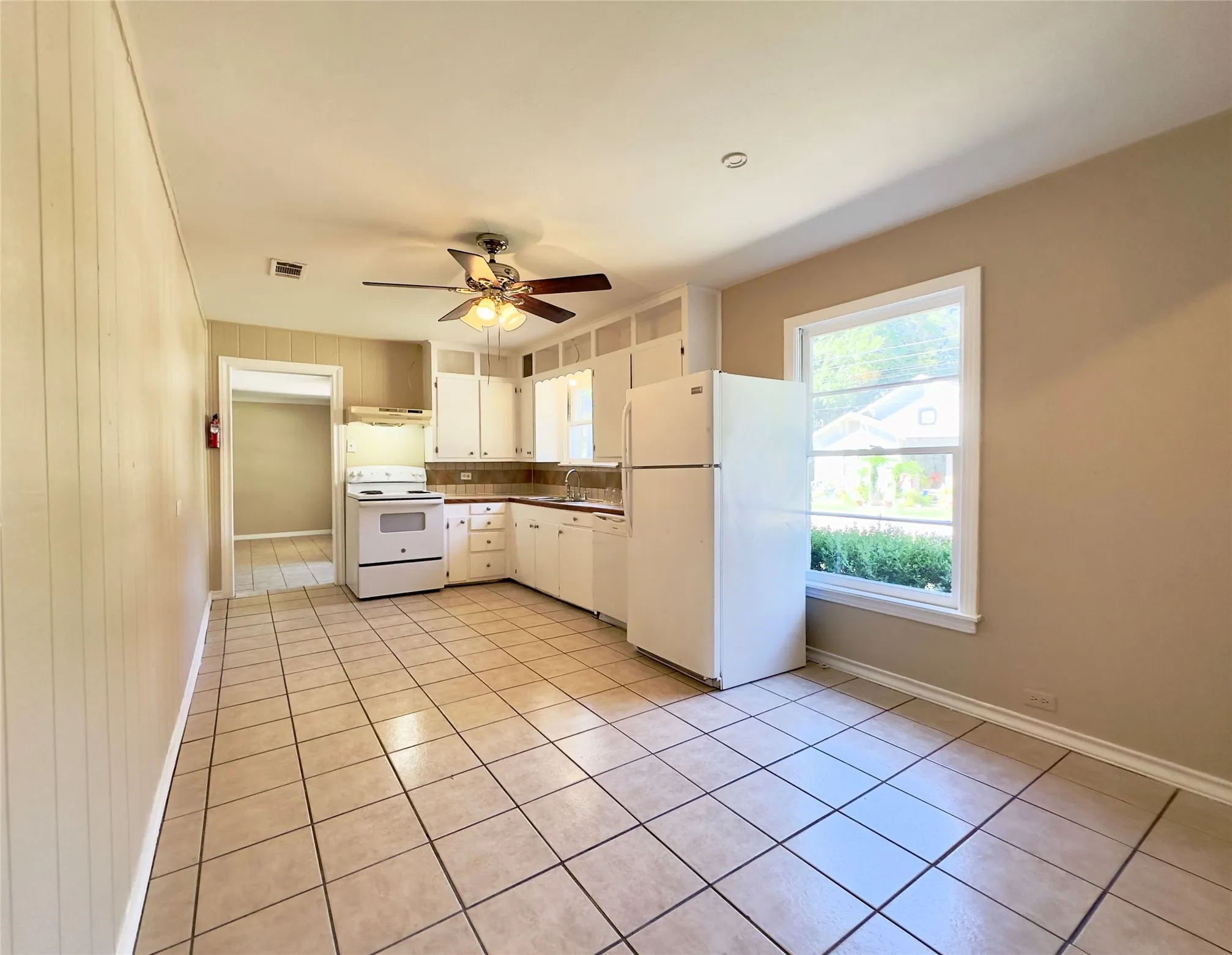 Kitchen featuring white cabinetry, tile flooring, white appliances, and a window