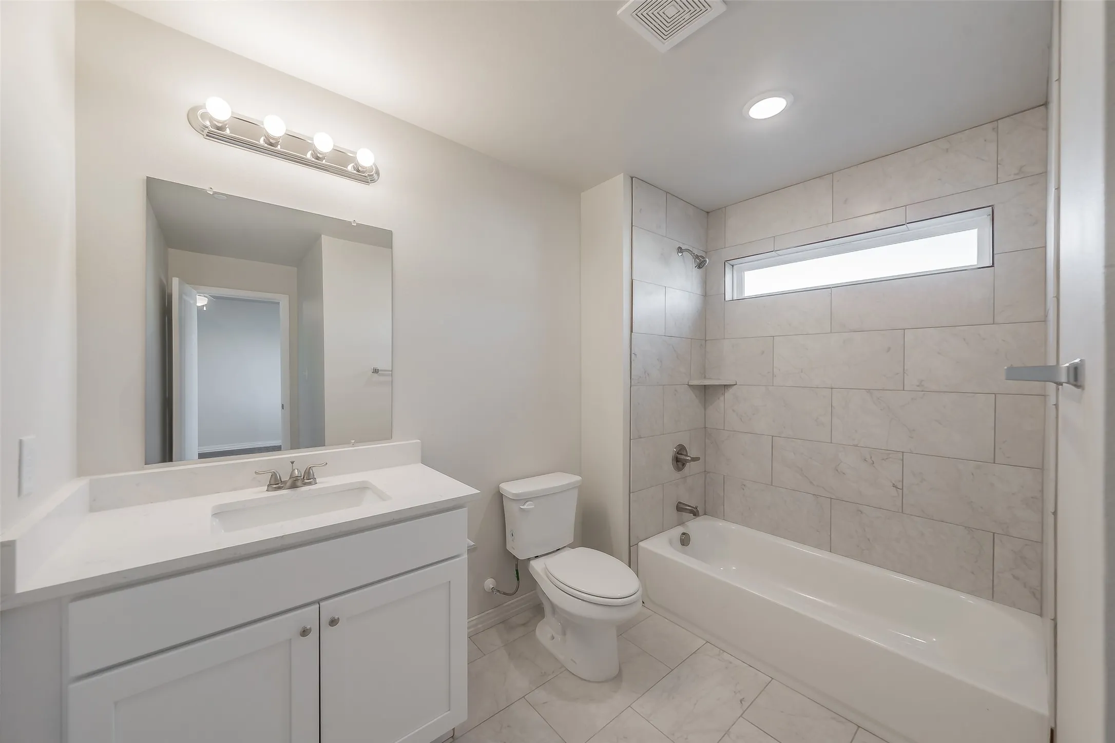 Full bathroom with tiled shower / bath combo, vanity, and toilet