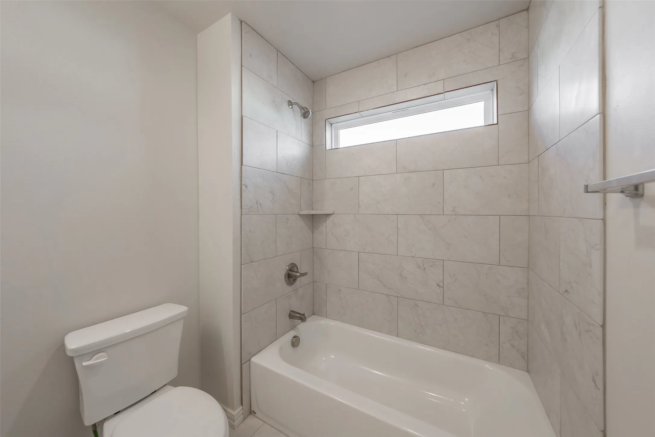 Bathroom featuring tiled shower / bath combo and toilet
