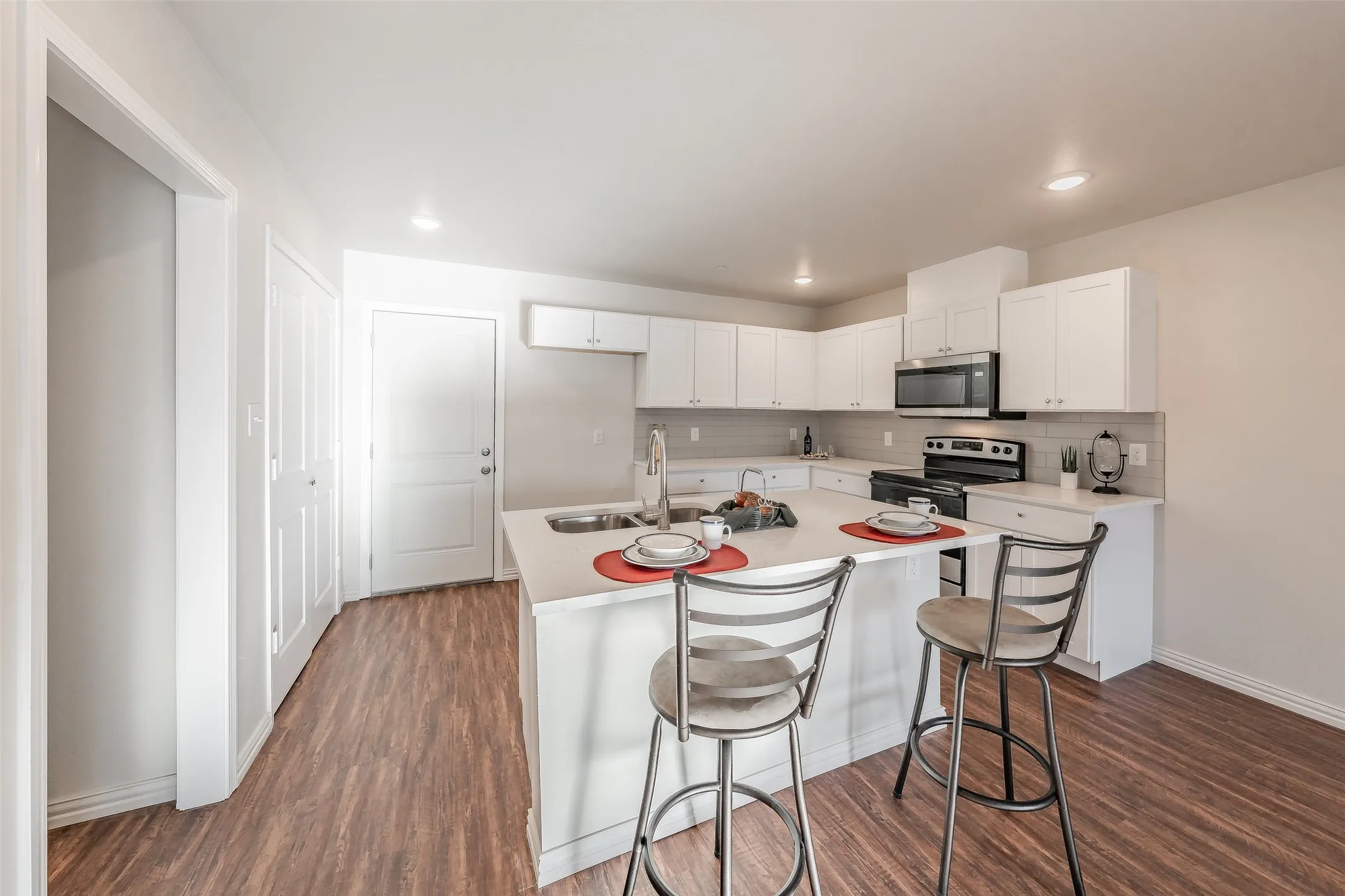Kitchen with white Shaker cabinets, stainless steel appliances, sink, and luxury vinyl dark hardwood / wood-style flooring