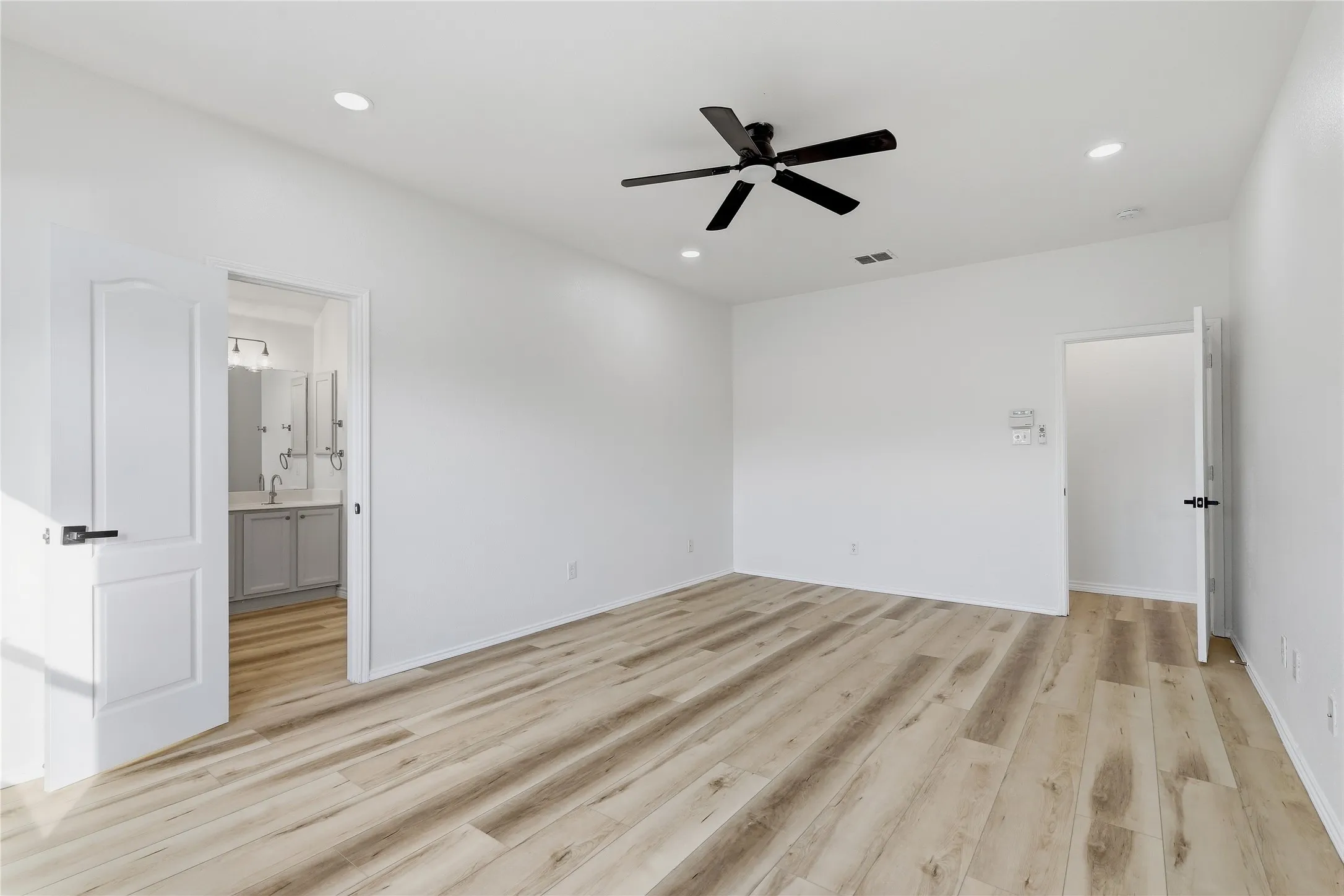 Spacious room featuring wood-finish flooring, recessed lighting, and a ceiling fan with a matte black finish