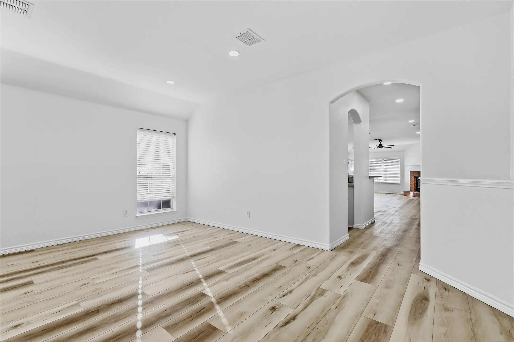 Light wood-finish flooring, recessed lighting, arched entryway, and a window with blinds