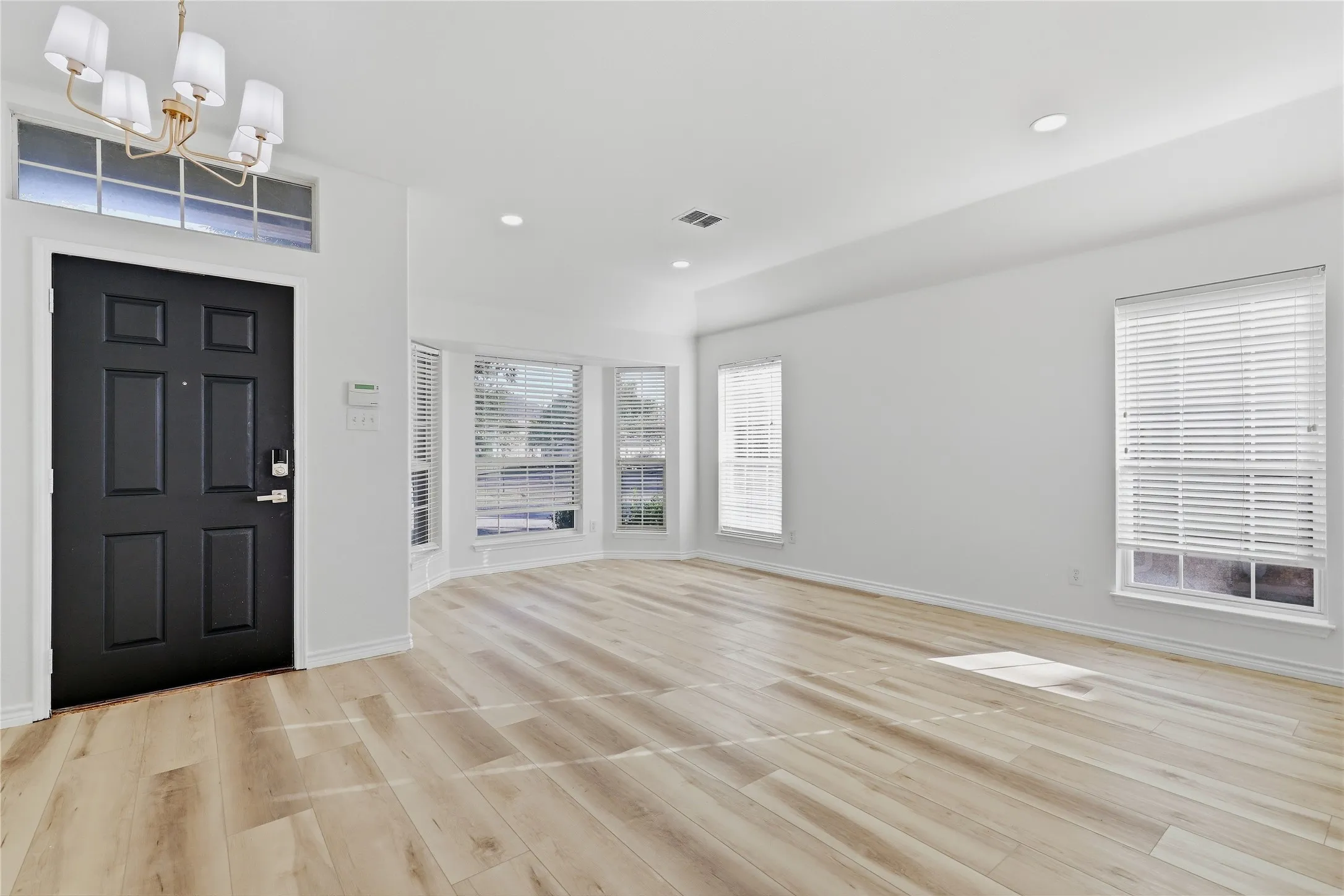 White walls with recessed lighting, wood-finish flooring, and multiple windows with blinds