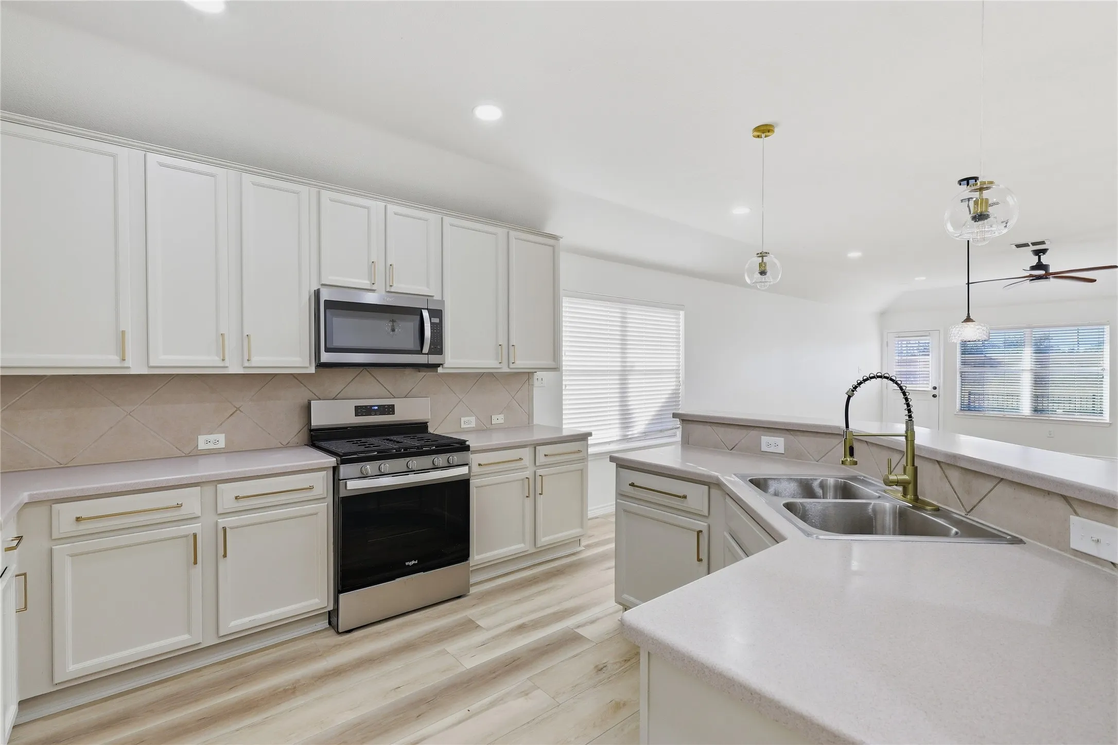 Spacious room featuring wood-finish flooring, recessed lighting, and a ceiling fan with a matte black finish