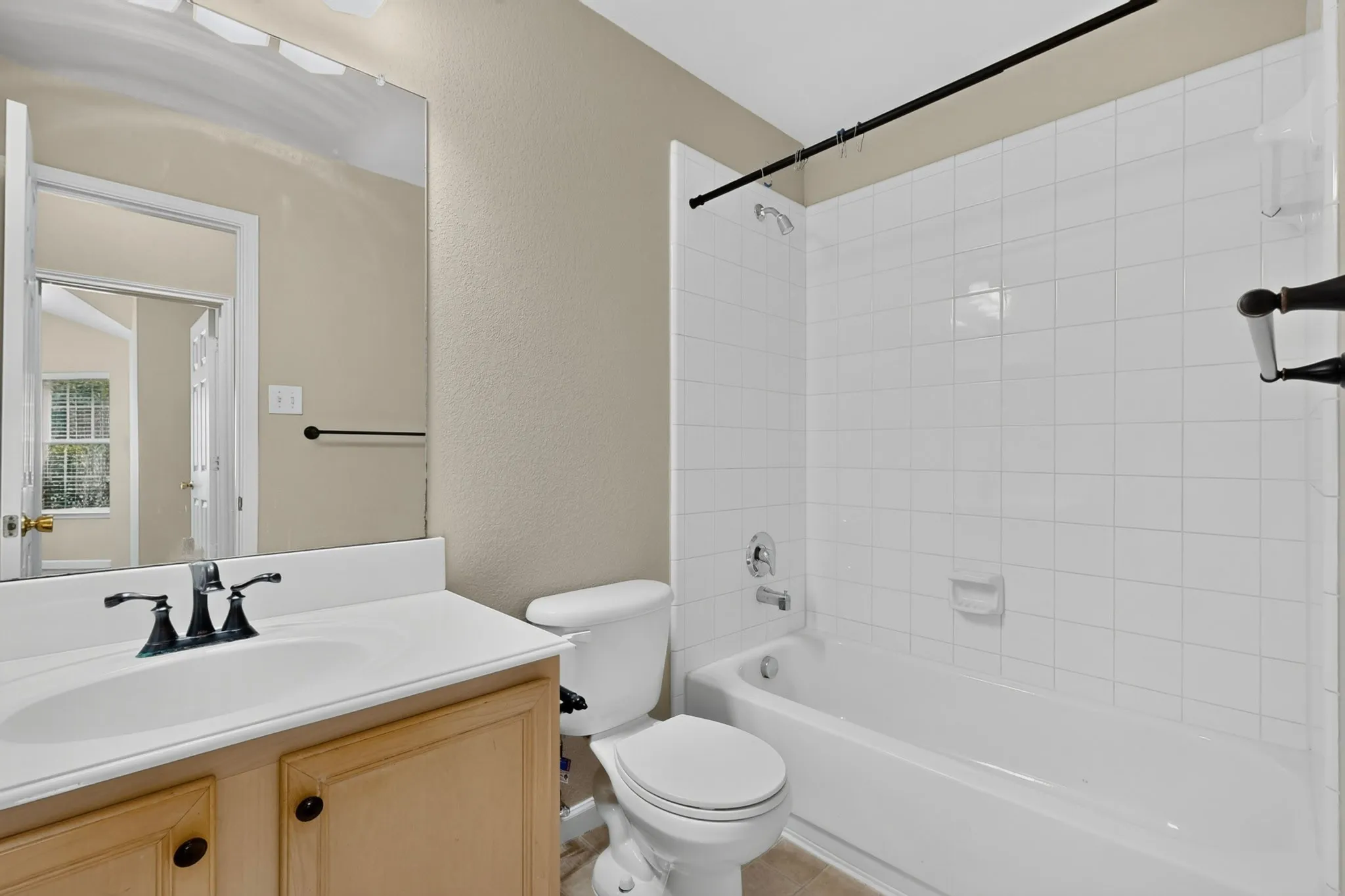 Bathroom featuring a built-in vanity with a white countertop and integrated sink, a commode, a shower/tub combination with white subway tile surround, and a wall-mounted mirror