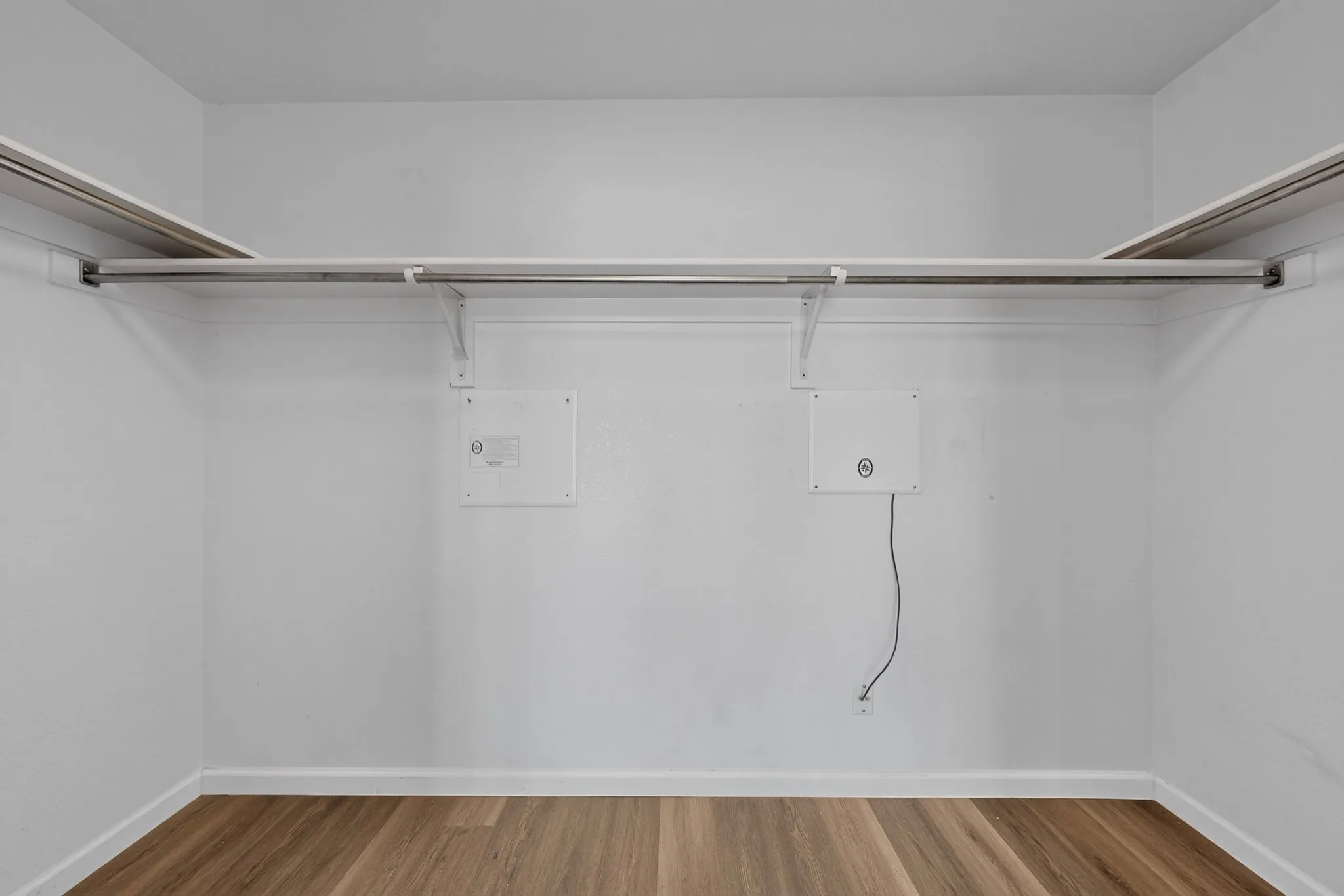 Closet featuring wood-finish flooring, white walls, and built-in shelving with hanging rods
