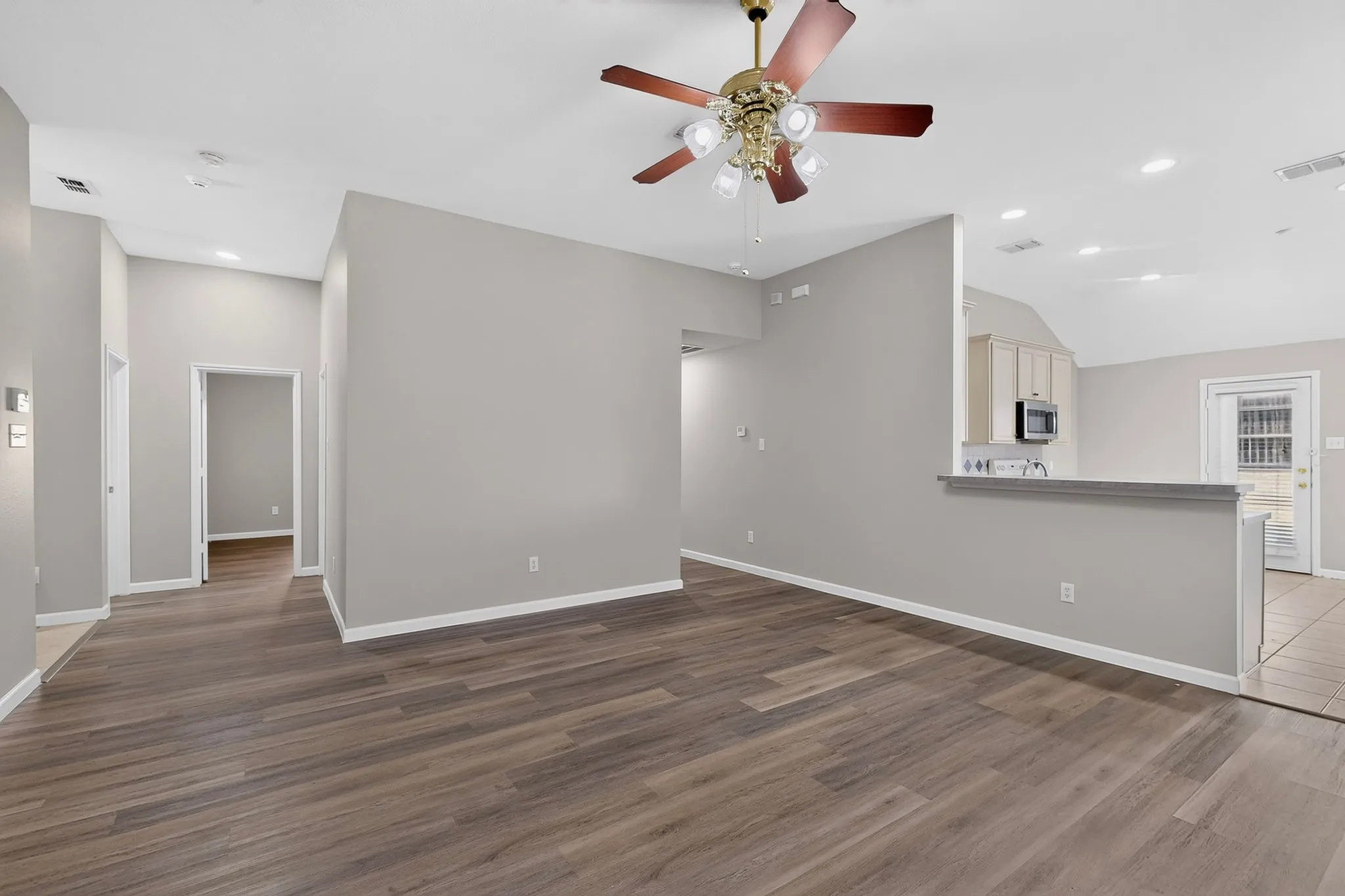 Wood-finish flooring throughout, vaulted ceiling, recessed lighting, and a ceiling fan with integrated lighting