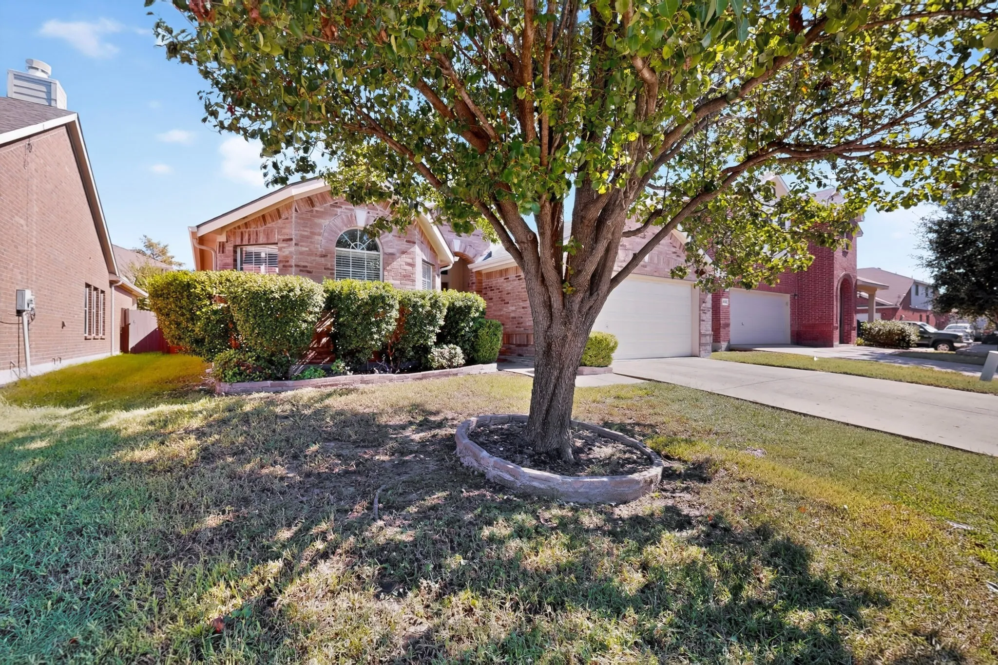 Brick exterior with an arched window, attached two-car garage, and a concrete​​‌​​​​‌​​‌‌​‌‌​​​‌‌​‌​‌​‌​​​‌​​ driveway