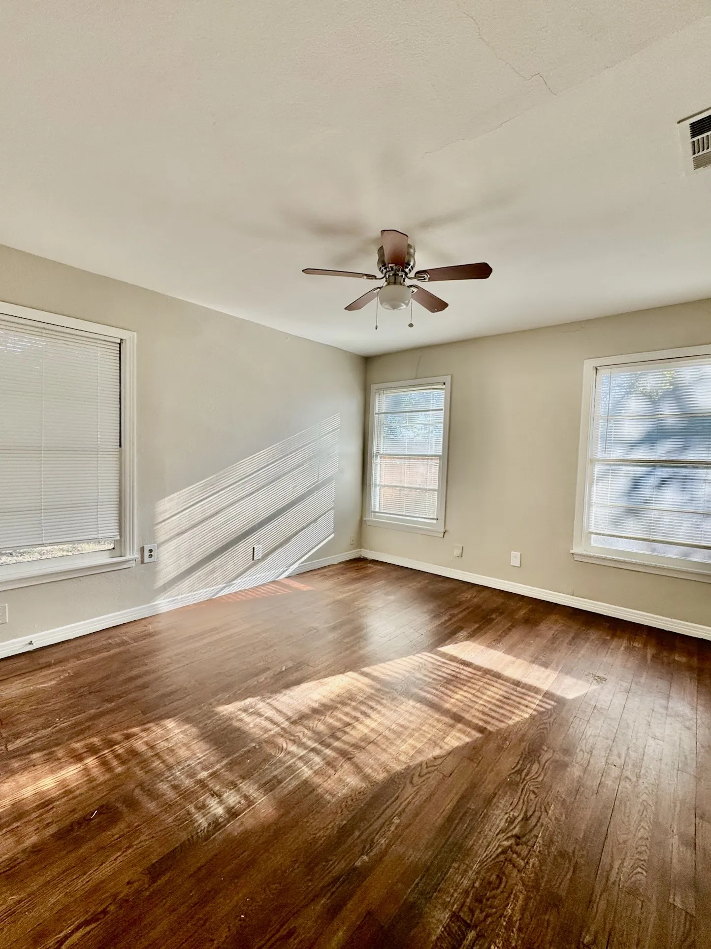 Spacious room featuring wood-finish flooring and multiple windows for natural light