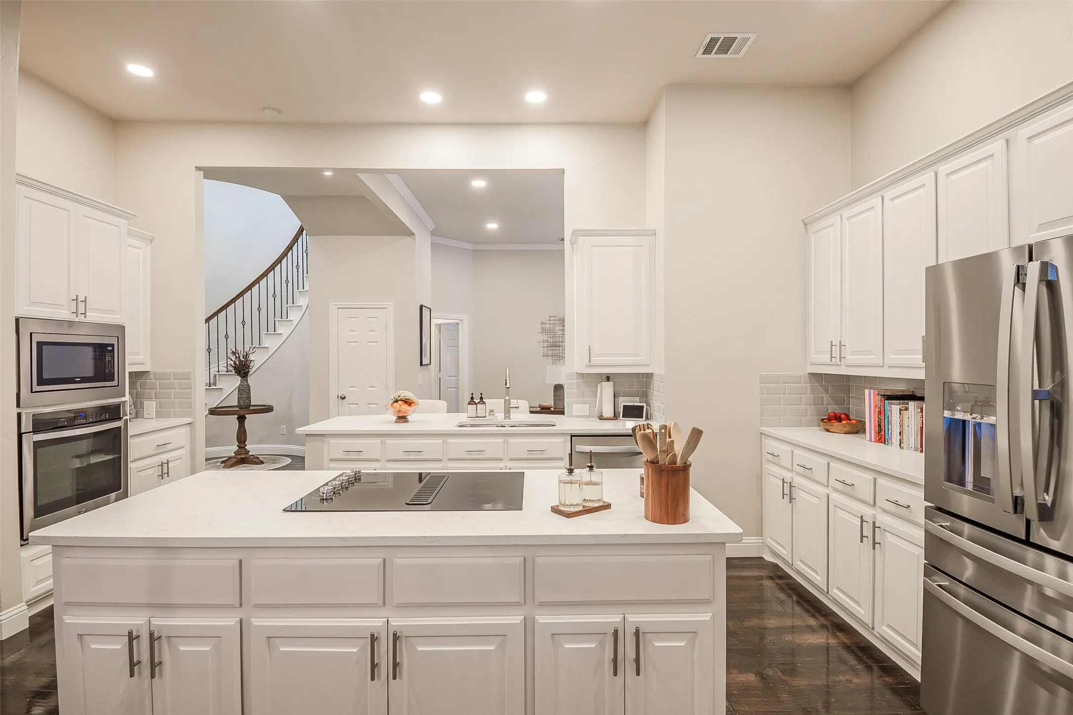 Kitchen featuring white cabinetry, light countertops, stainless steel appliances, a built-in oven, and wood-finish flooring