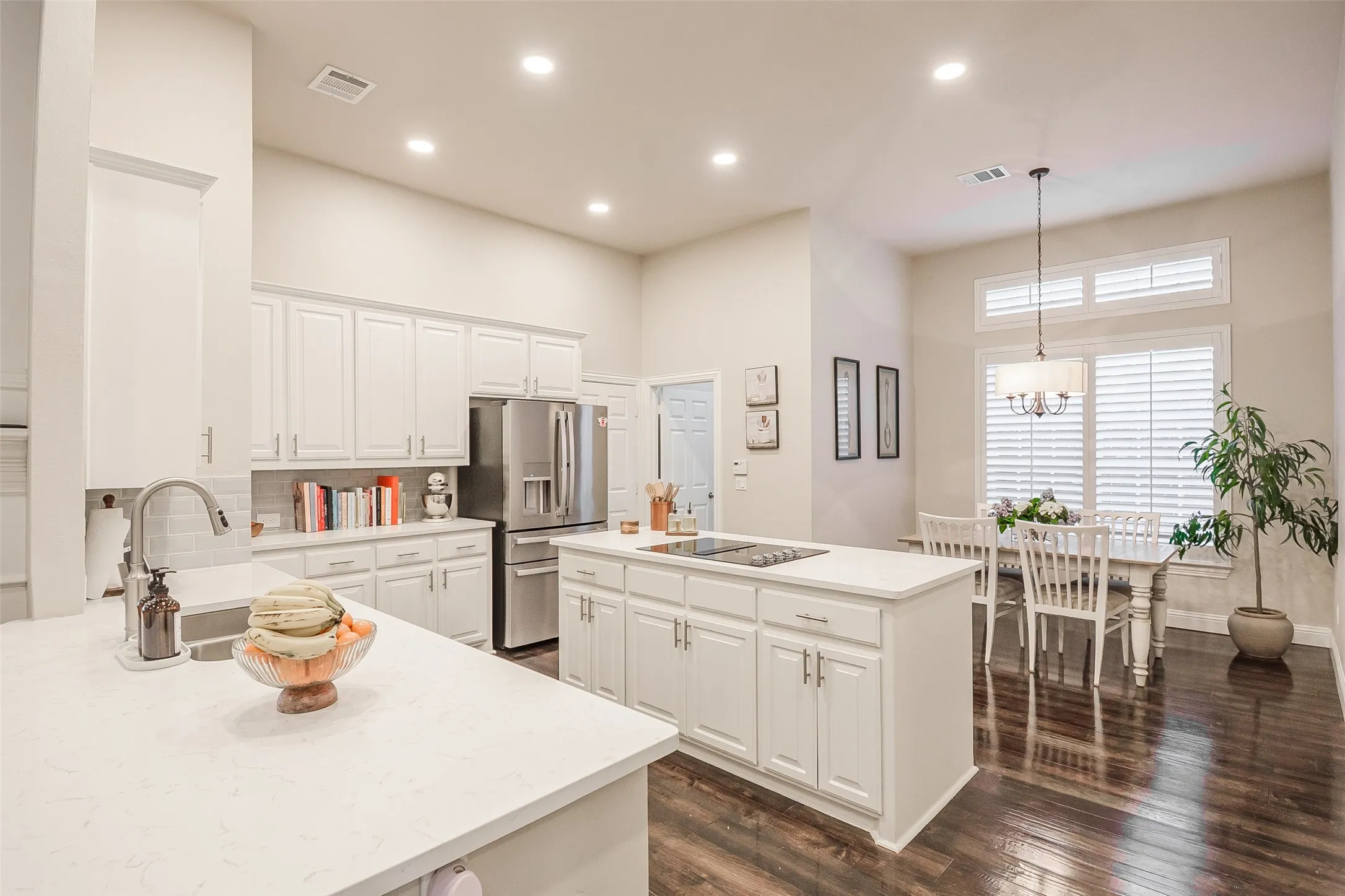 Kitchen with white cabinetry, stainless steel appliances, and a central island with a cooktop