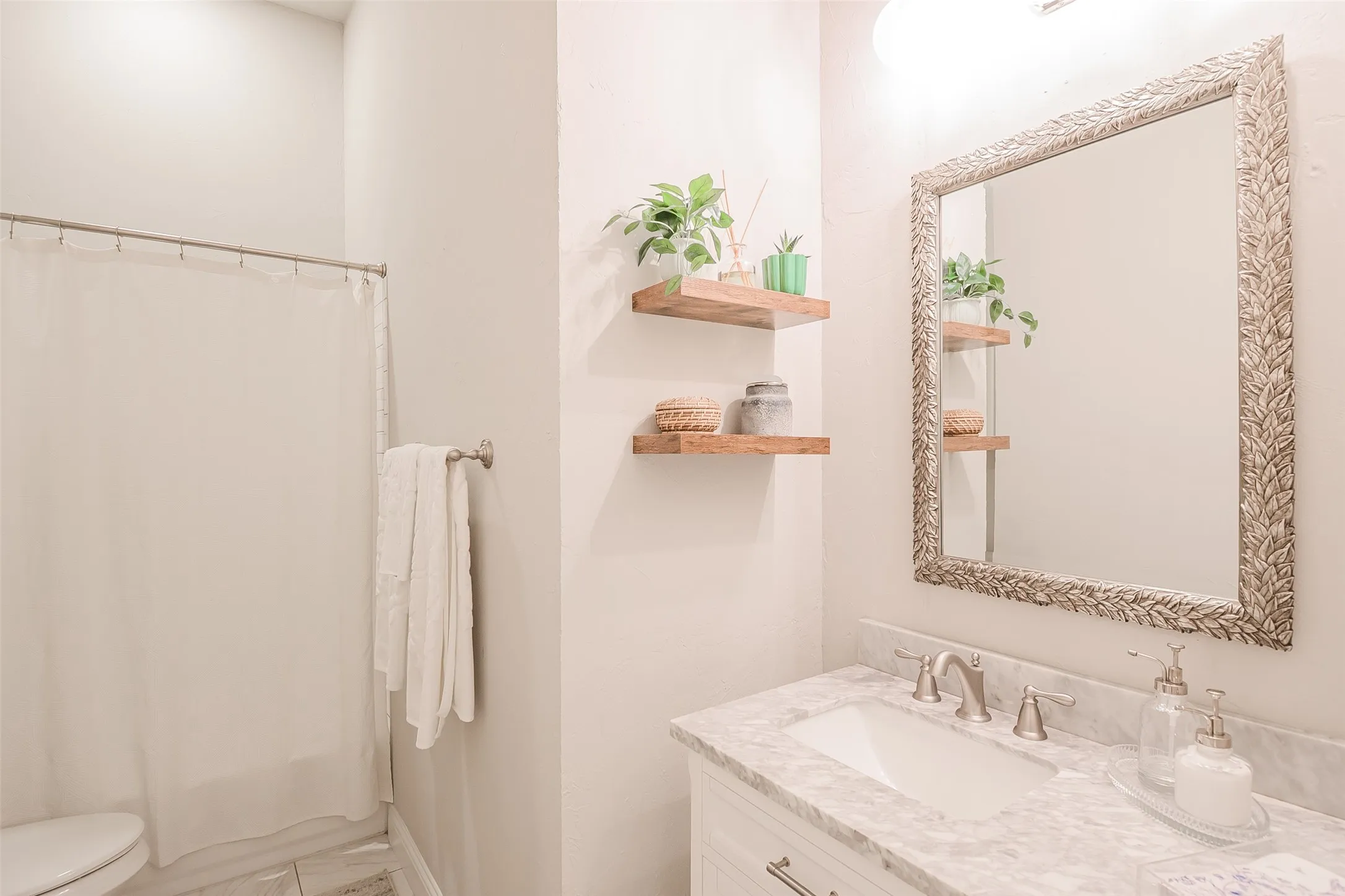 White vanity with a light-toned countertop, undermount sink, and brushed nickel faucet