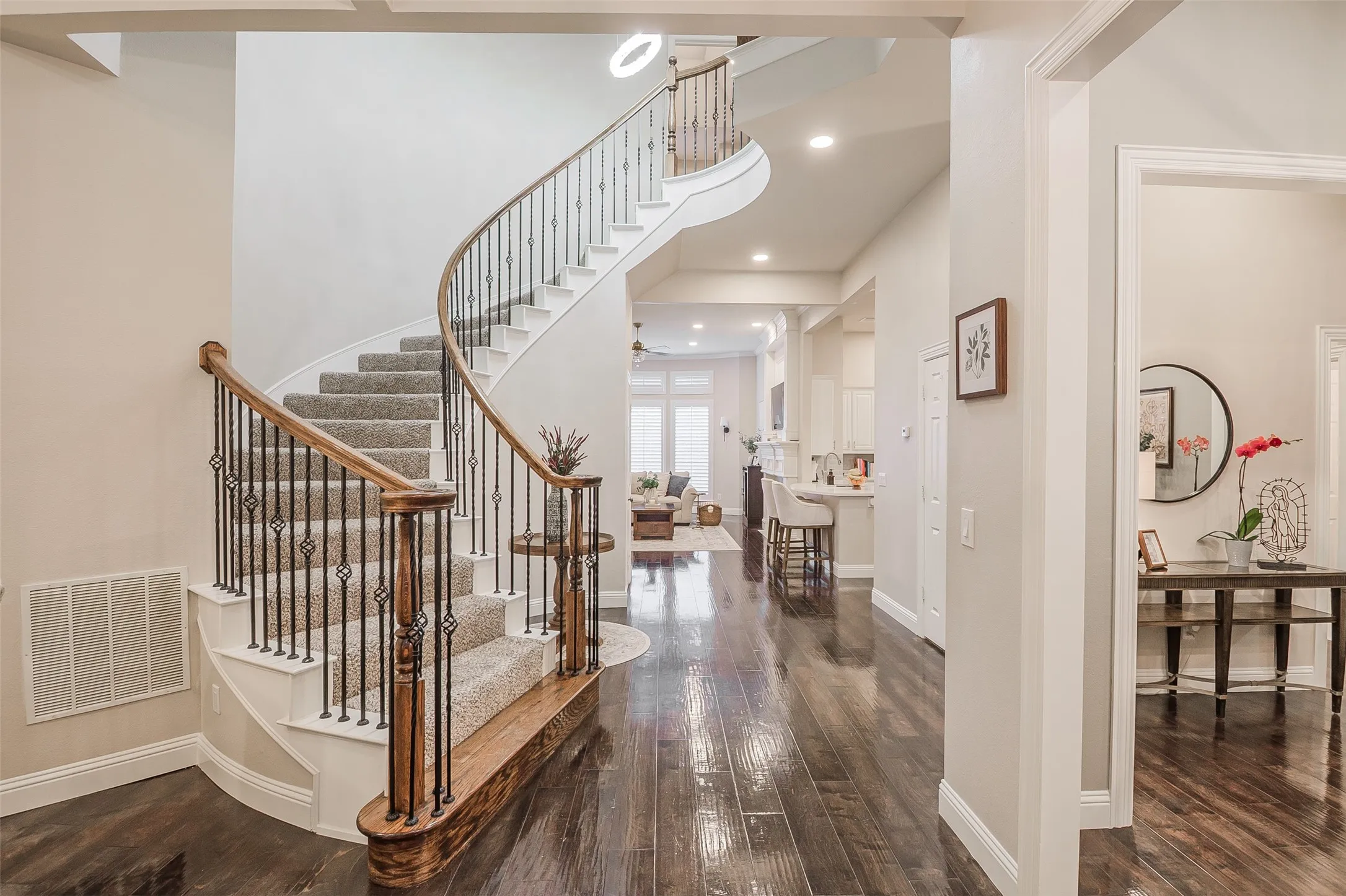 Hardwood flooring, curved staircase with wrought iron balusters, recessed lighting, and crown molding