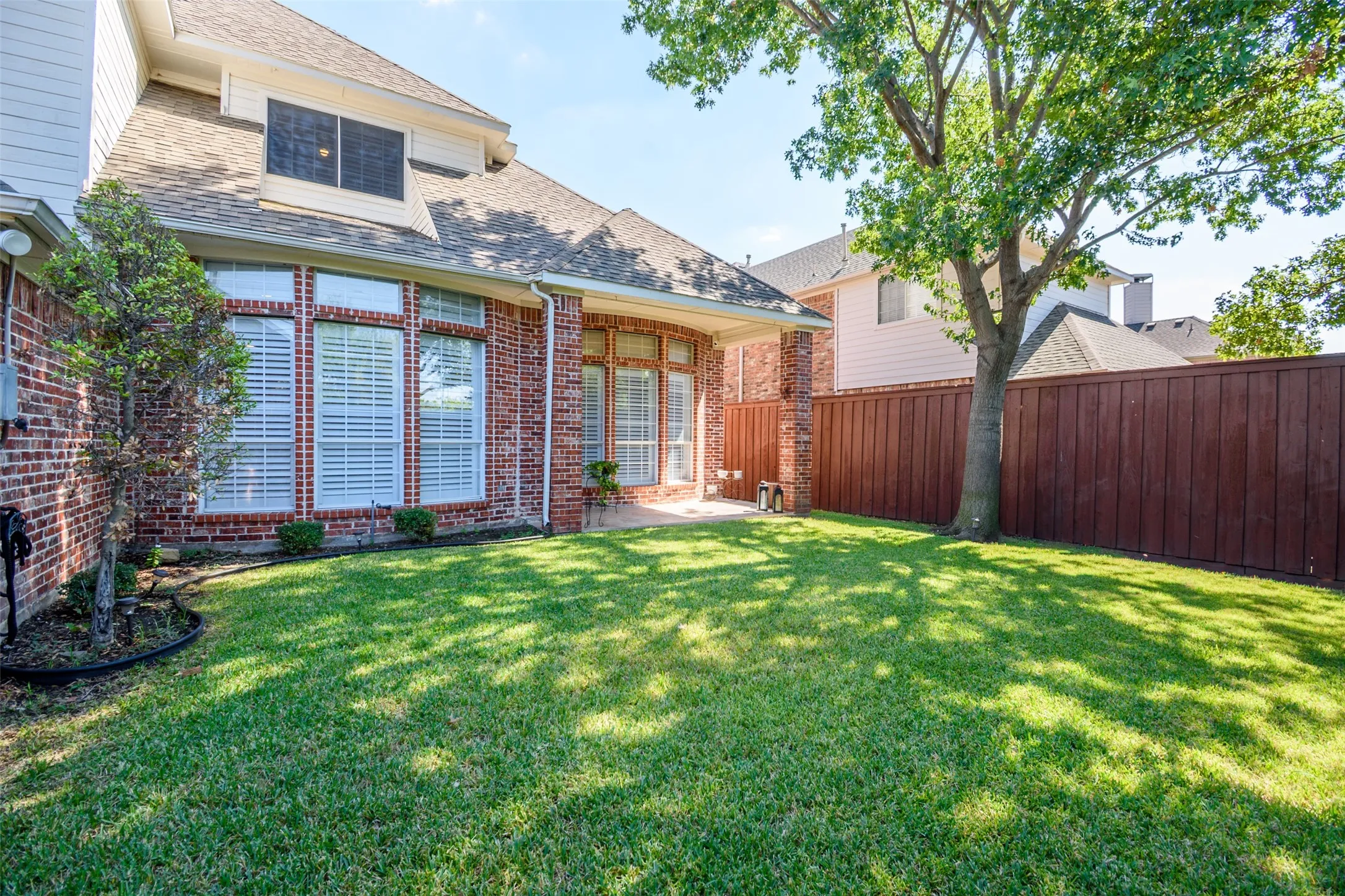 Expansive grass yard with a wood fence and mature trees