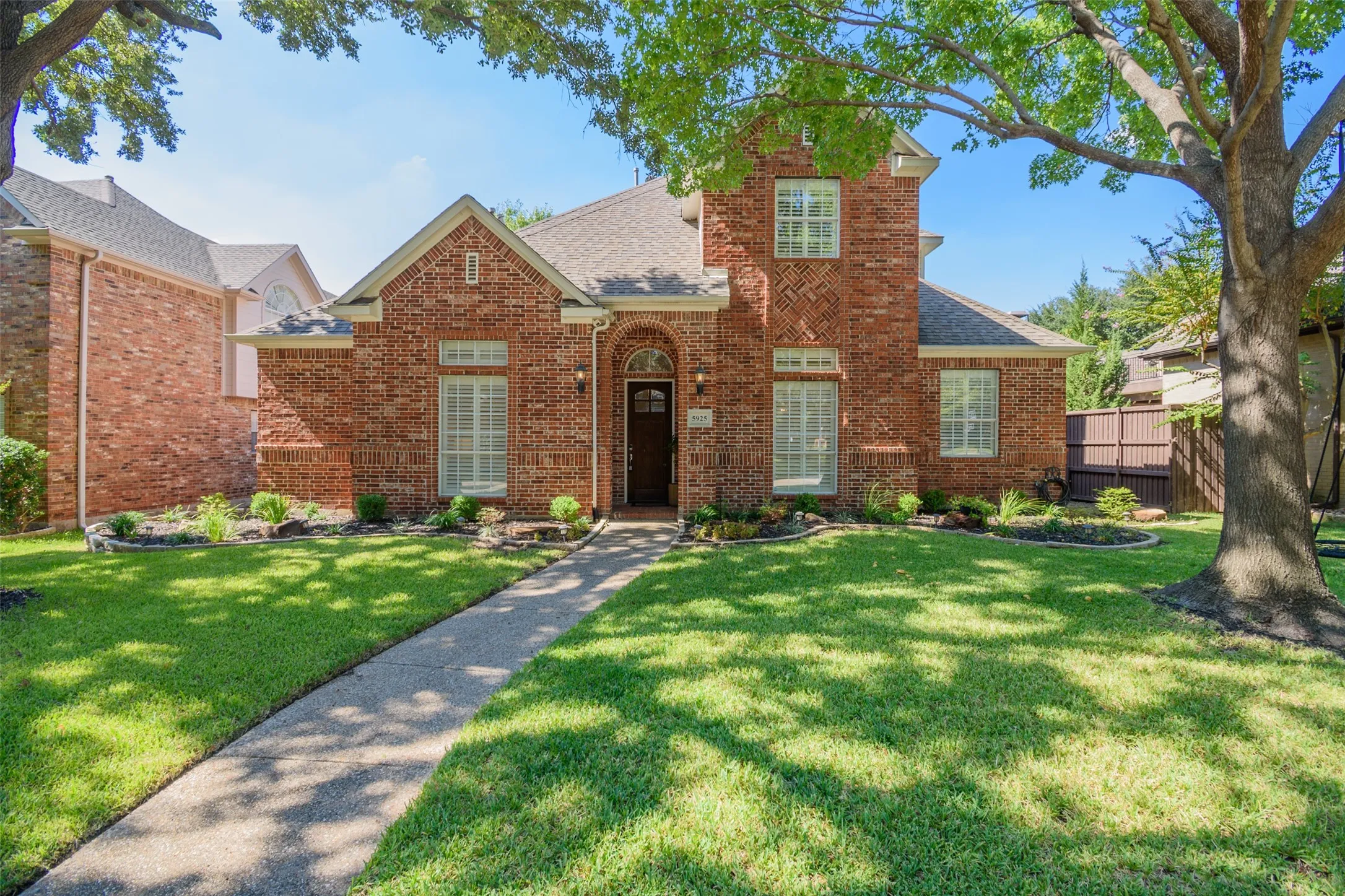 Red brick exterior with white window trim and a dark wood-finish front door