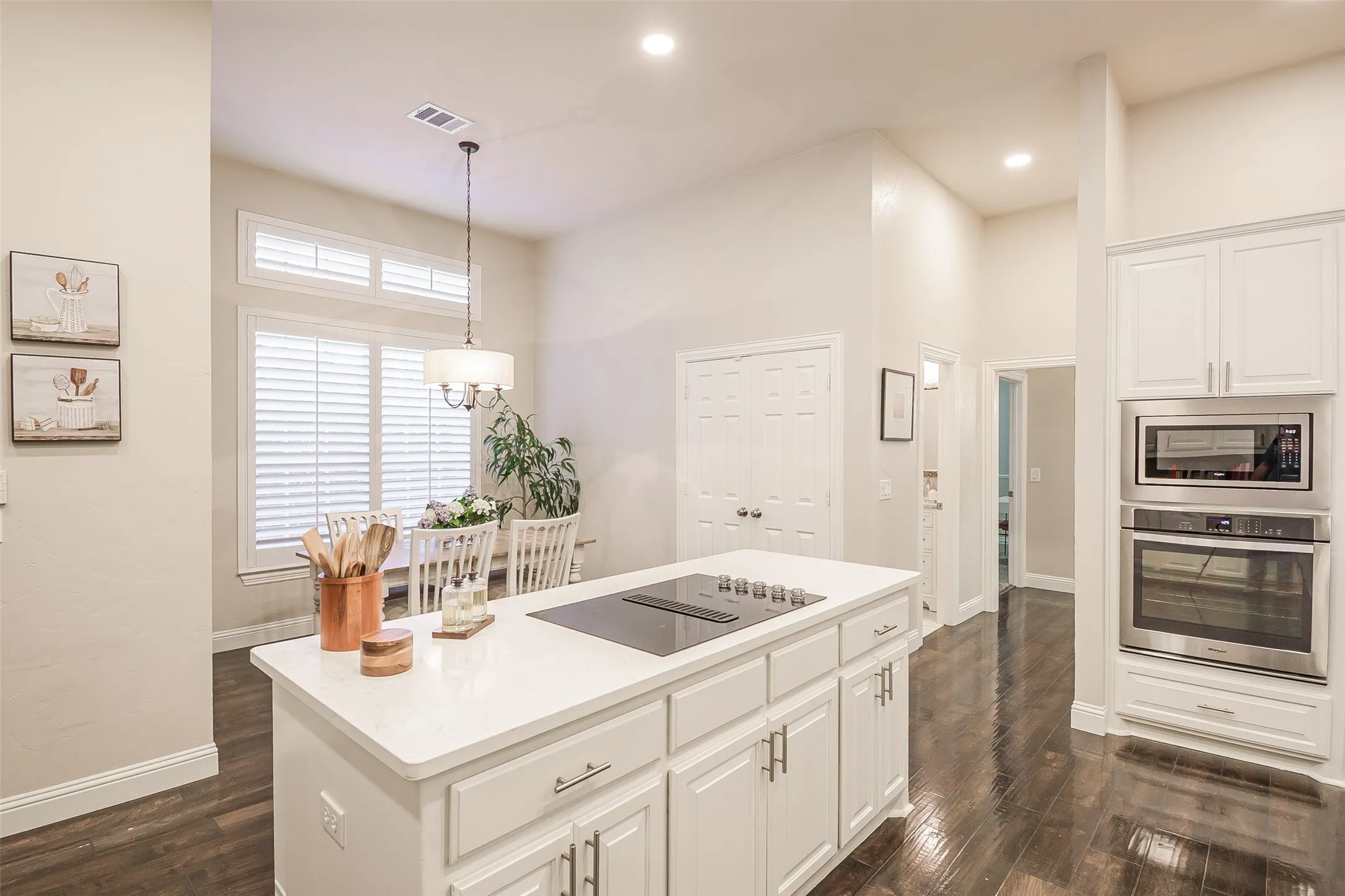 Contemporary kitchen featuring a large center island with white cabinetry and quartz countertop, stainless steel sink, and pendant lighting
