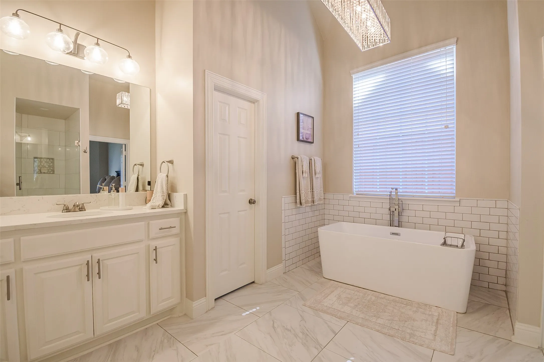 Freestanding soaking tub, subway tile wainscoting, and a single vanity with a quartz countertop